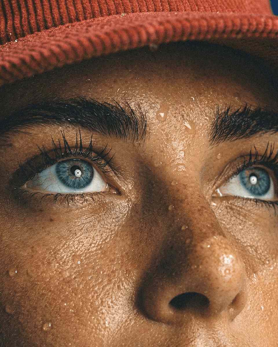 Close-up of a person's face with dramatic lighting, focusing on their expressive eye and detailed skin texture.