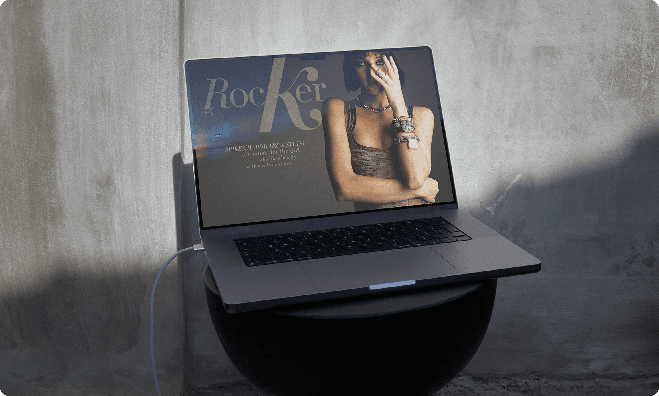 Laptop displaying Neiman Marcus 'The Rocker' editorial featuring model with jewelry and spikes, hardware & studs styling