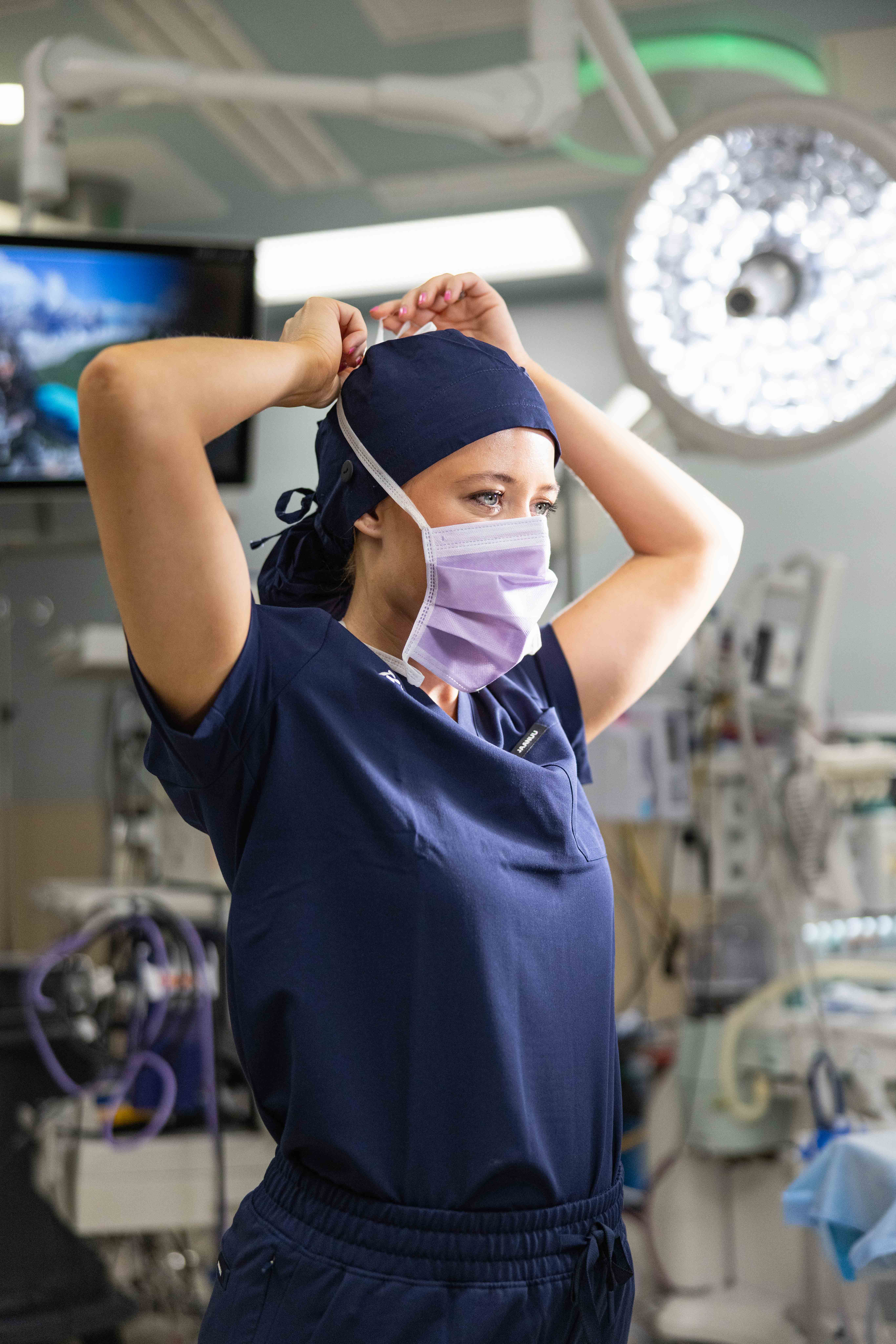 CRNA adjusting surgical mask in a hospital operating room