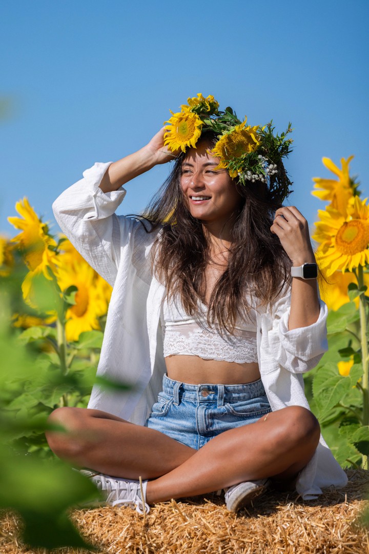 Woman holding flower crown in sunflower field
