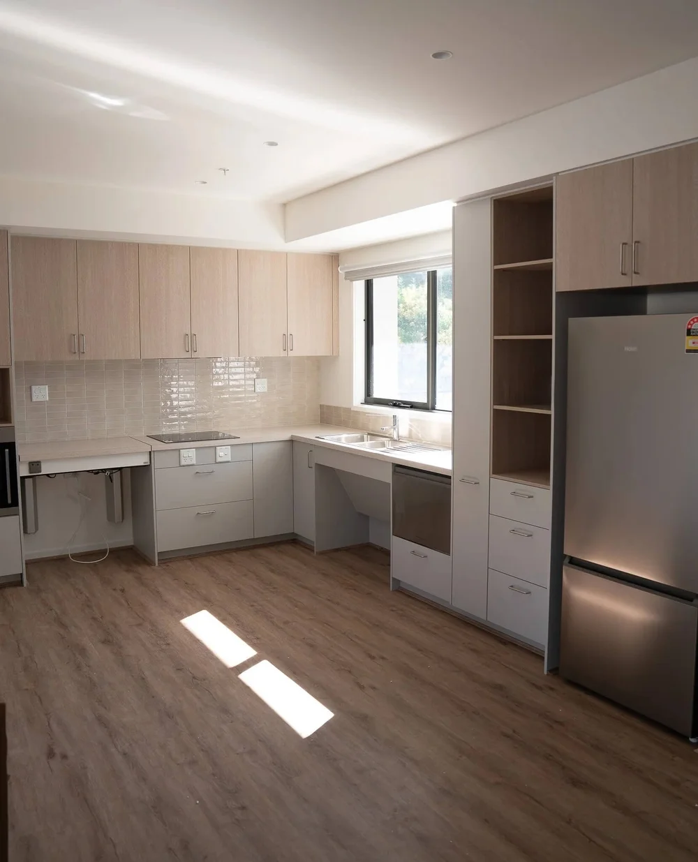 Modern kitchen with wood cabinets, stainless steel appliances, and light laminate flooring.