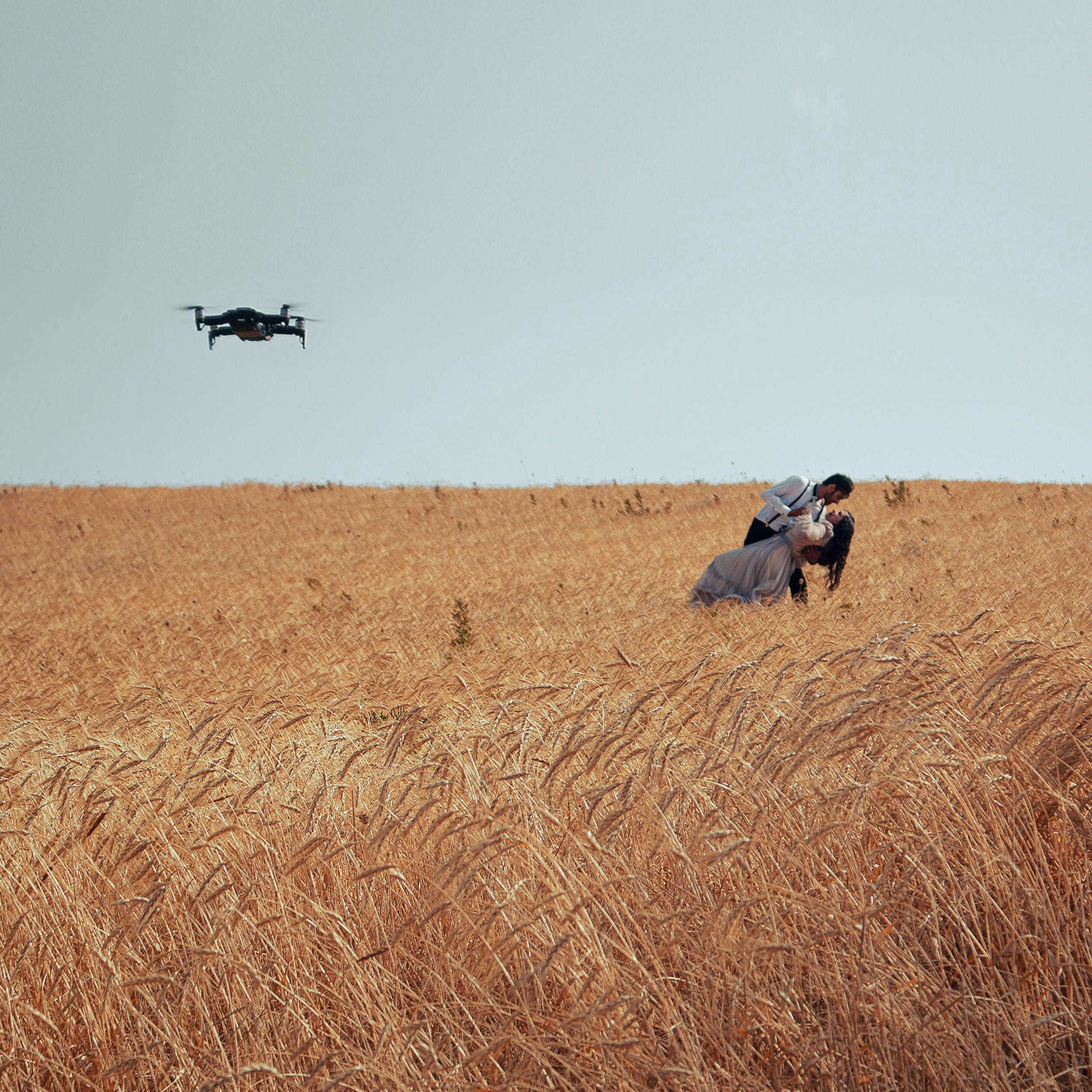 two people in a field with a helicopter in the background