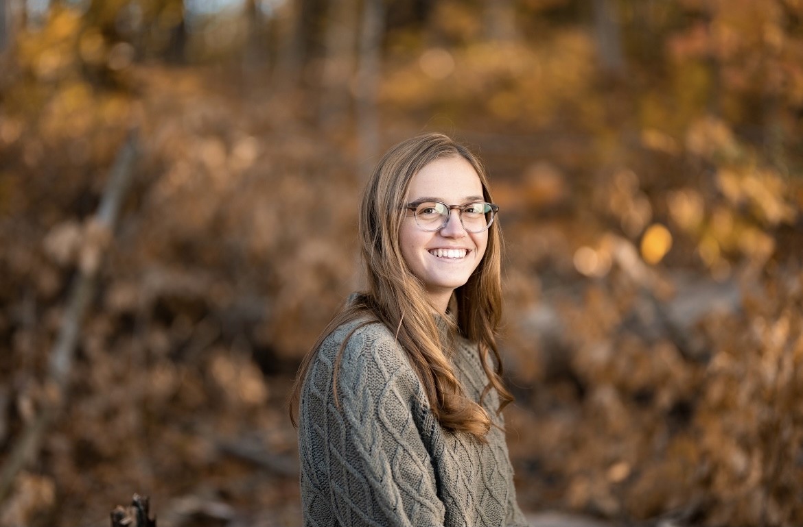 A thoughtful young person with dark hair gazes to the side, captured in soft black and white lighting.