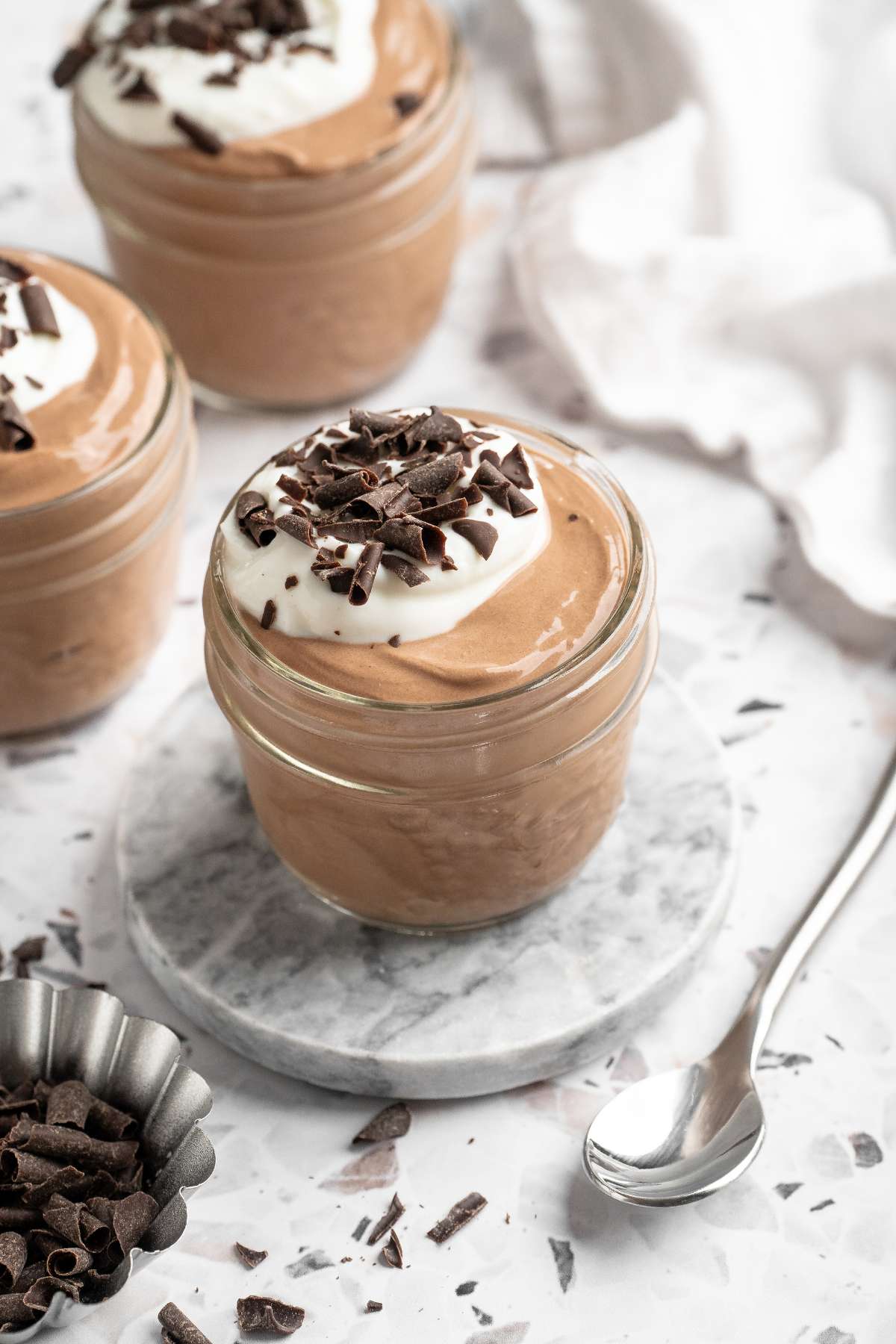 Double chocolate cottage cheese mousse in a small glass topped with Greek yogurt and chocolate shavings.
