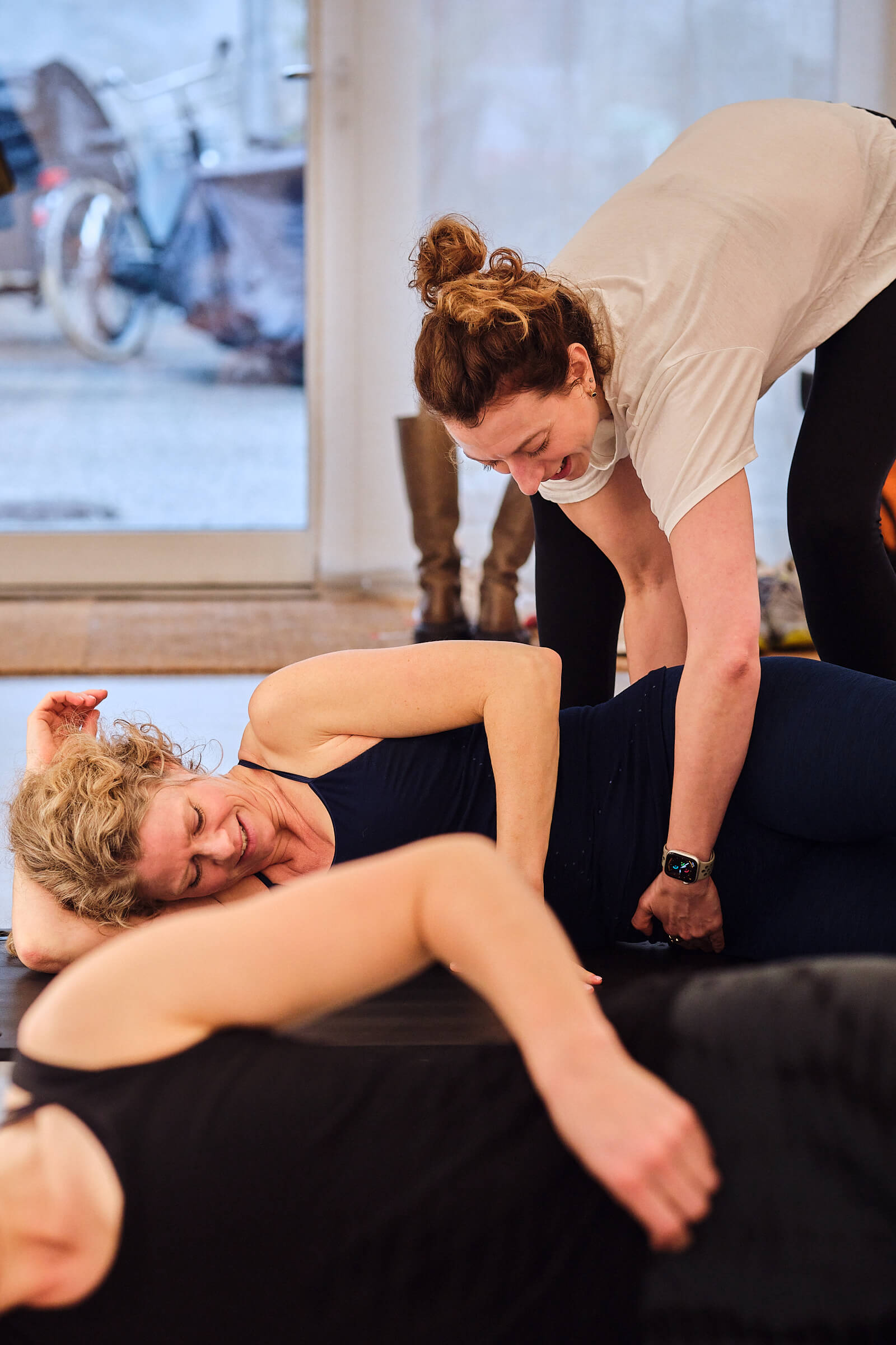 Pilatesinstruktør guider kvinde i pilatesøvelse på måtte