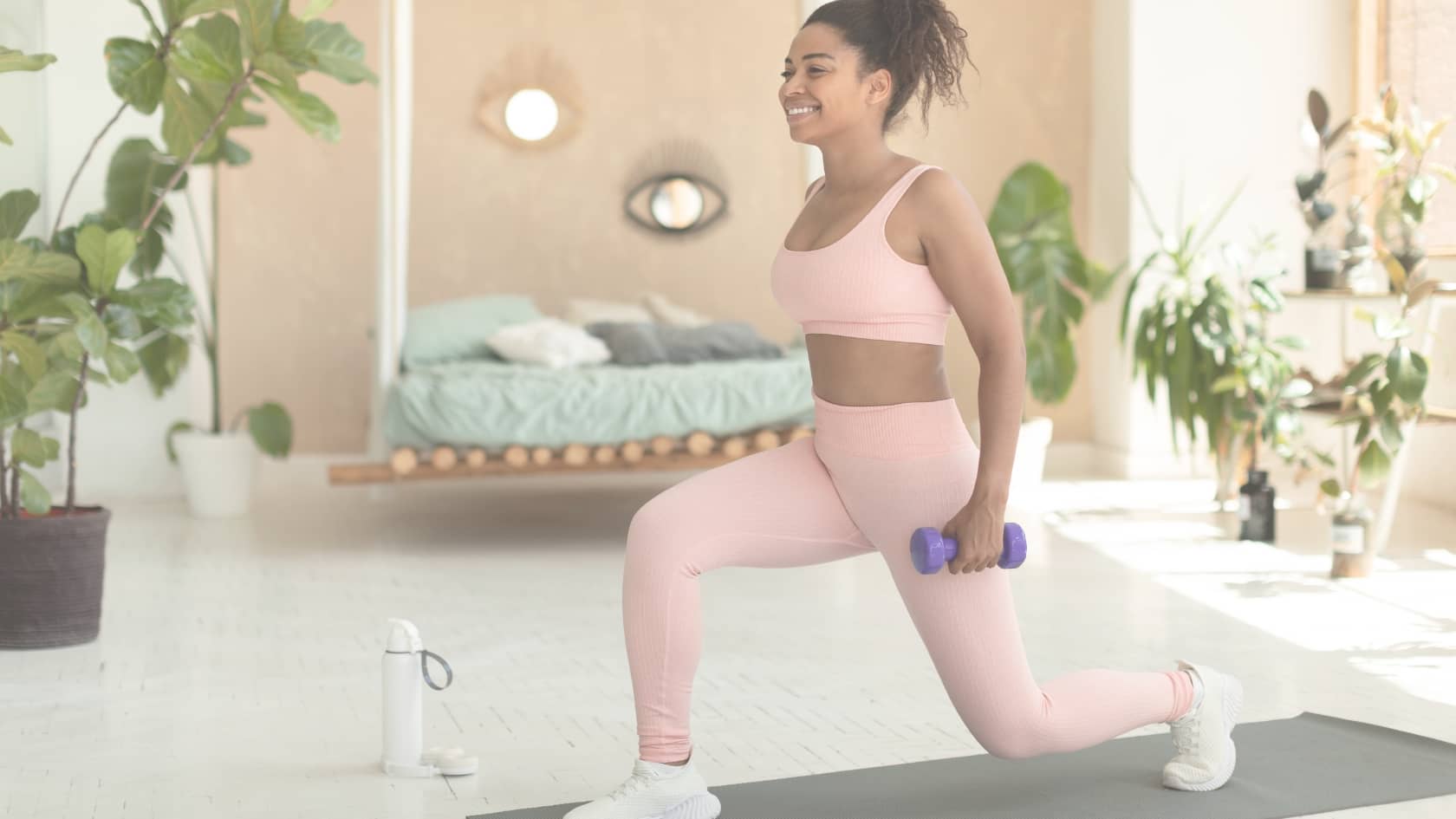 Femme ayante de la motivation pour faire du sport à lai maison, en tenue de sport et avec des haltères