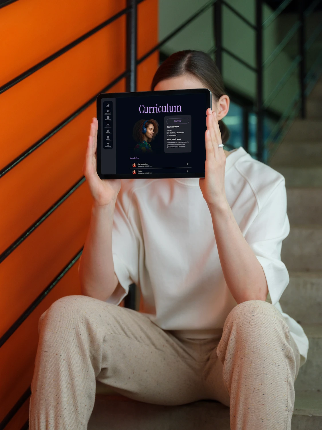 A woman holds a horizontal tablet showing the Learnoverse curriculm