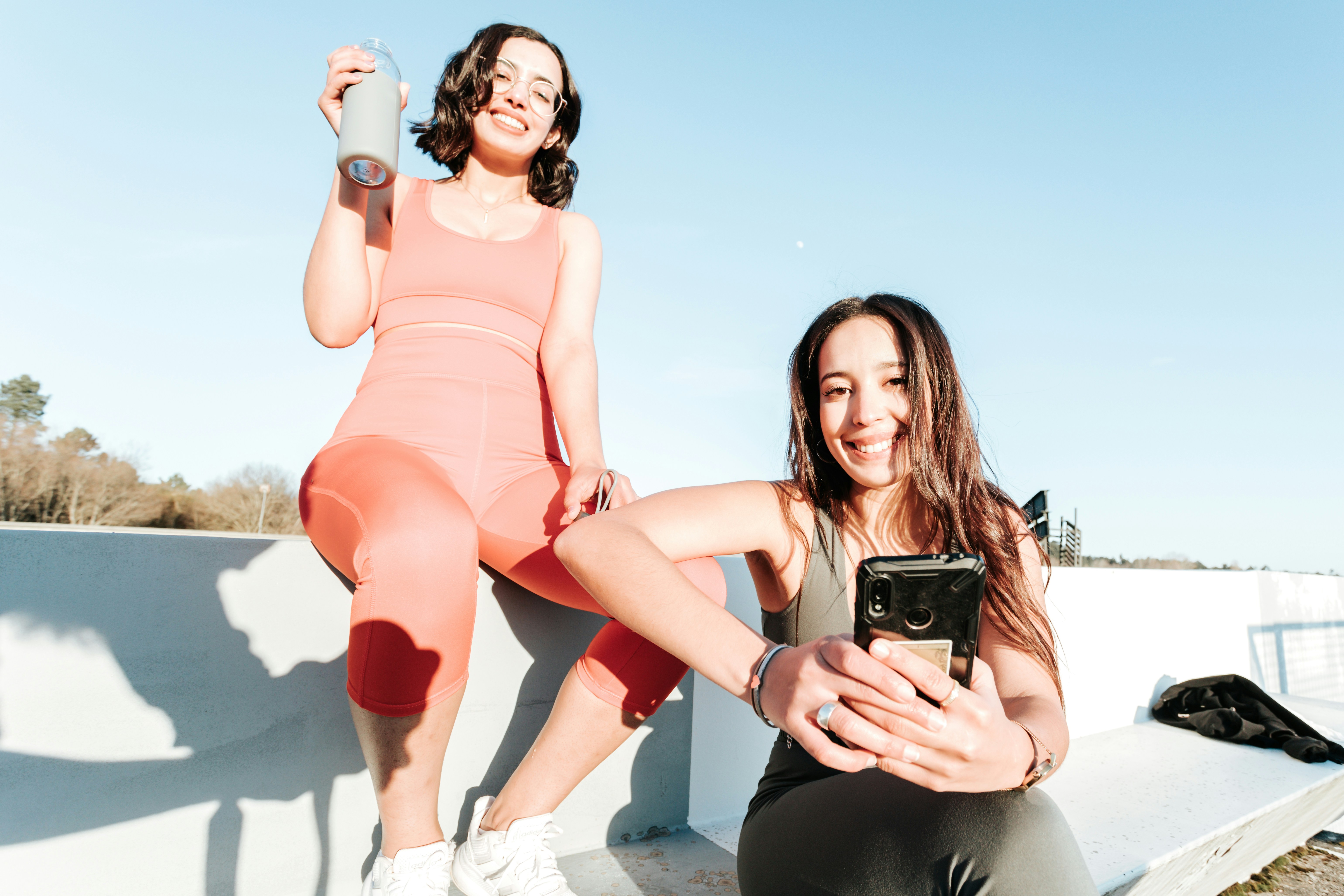 A woman holding a medicine ball with a trainer watching.
