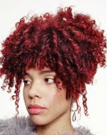 A model with curly red hair tied up.