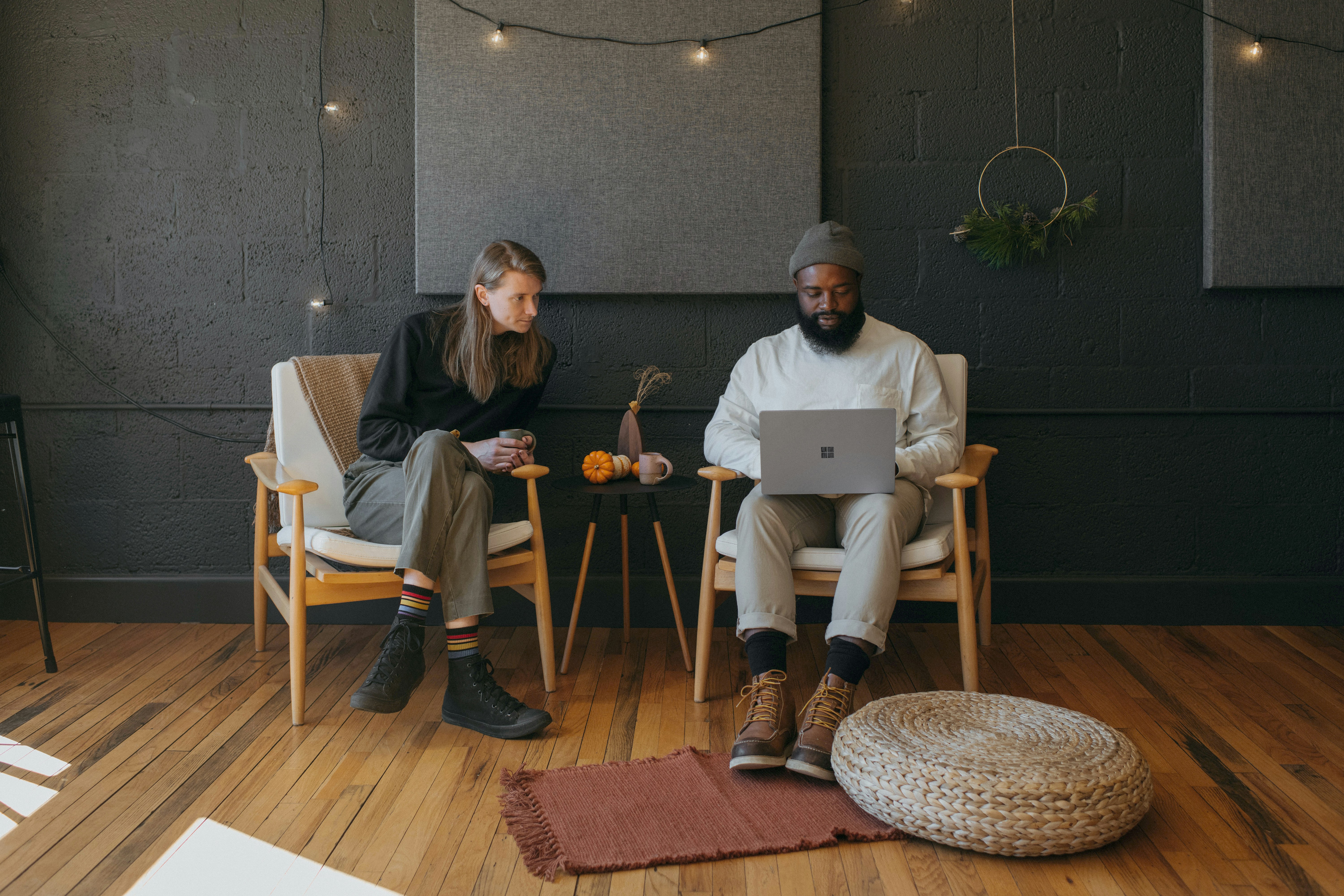 Two coworkers collaborating sitting on chairs holding a Surface laptop with Christmas decorations in the background