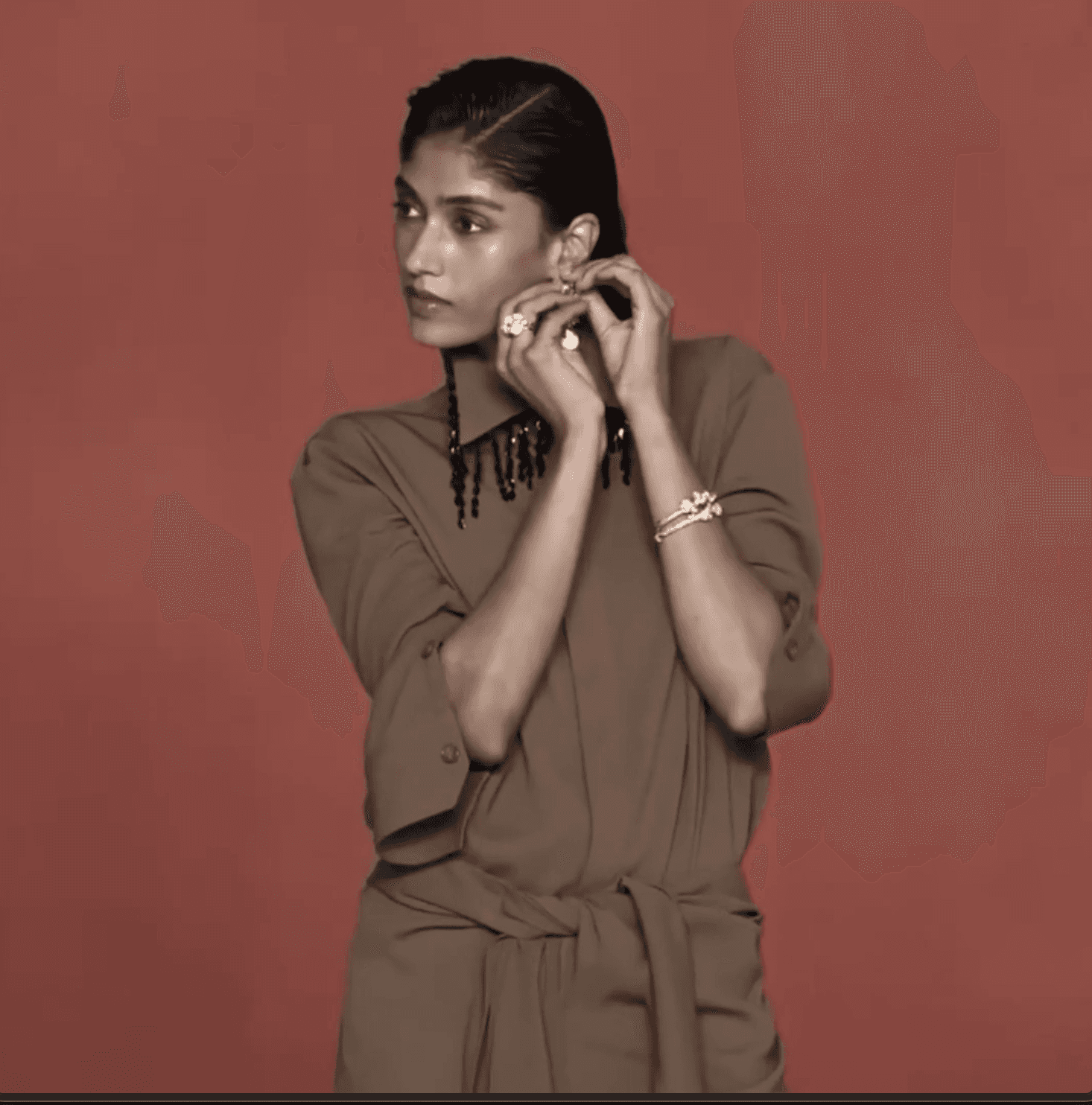 Model in sculptural silhouette against muted red backdrop, reflecting 431-88’s quiet strength