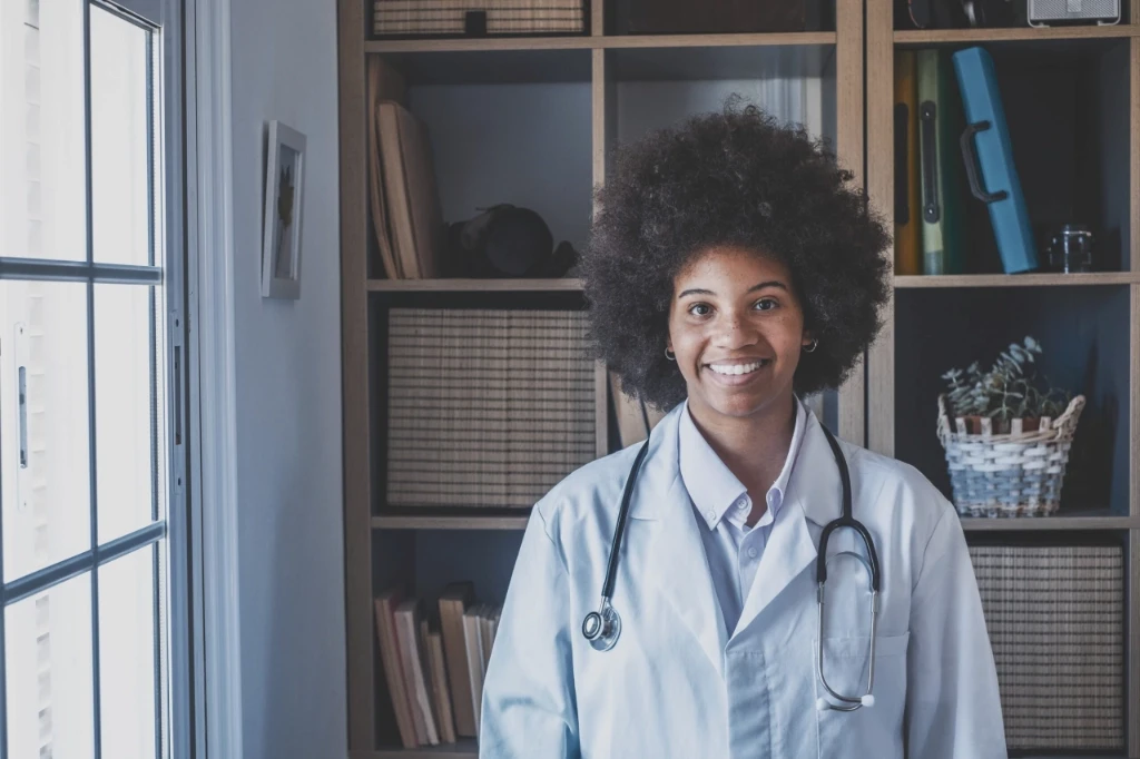 Female doctor standing in front of bookcase smiling at camera