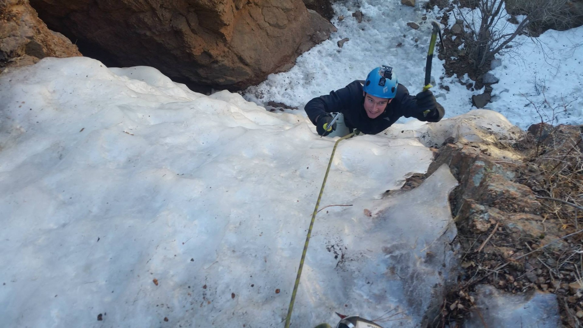 Ice climber swings their ice tool near the top of Hully Gully ice climb