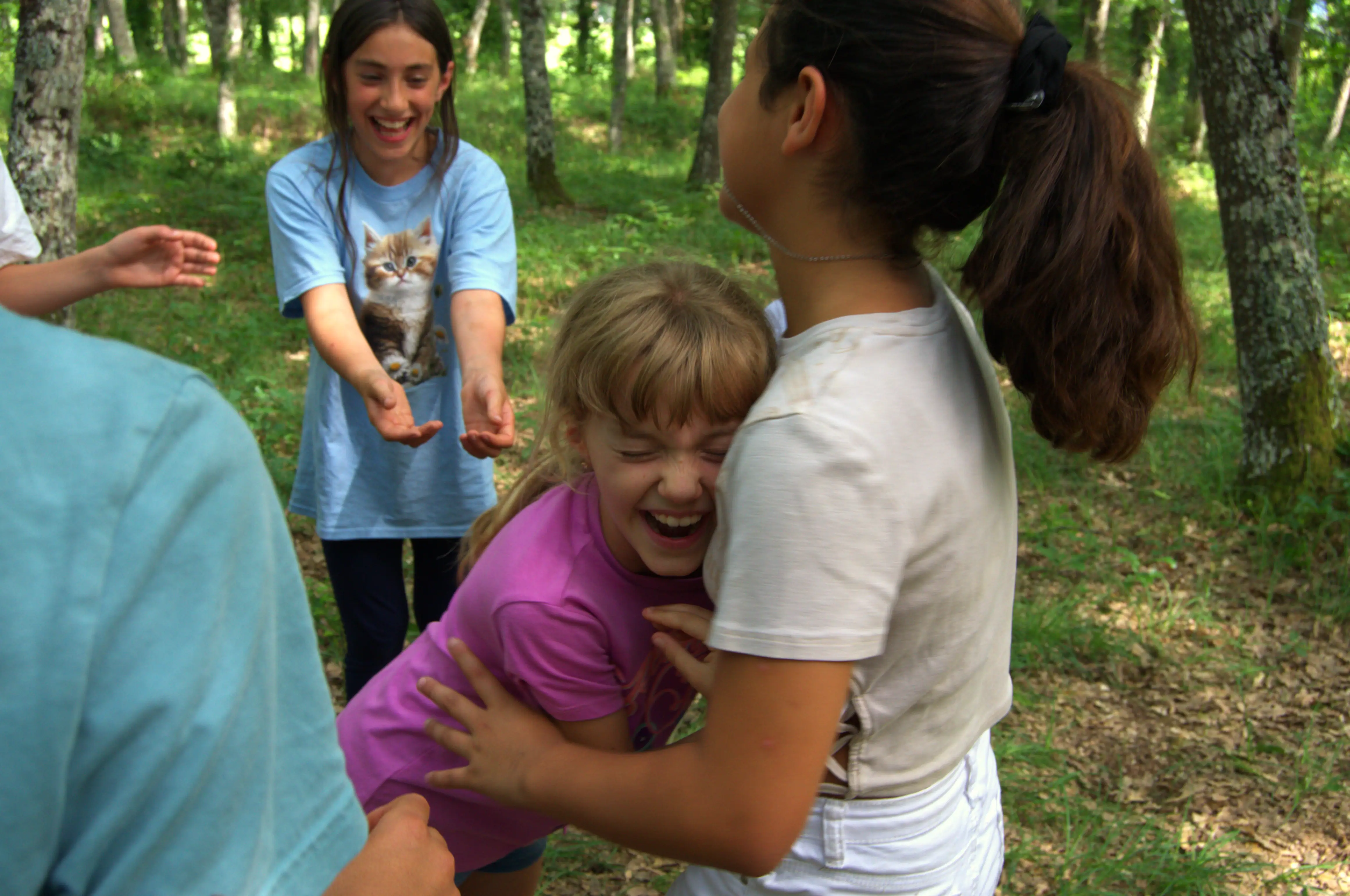 Bambine felici che si abbracciano durante campo estivo, testimonianza delle esperienze positive di outdoor education e campi avventura per ragazzi