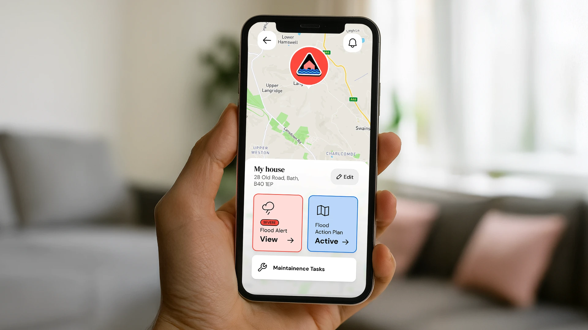 Person holding a smartphone showing the Resilico app with flood alerts and safety options.