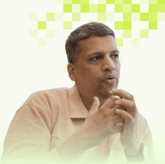 Man with short dark hair wearing a light green shirt, sitting near a window in soft light