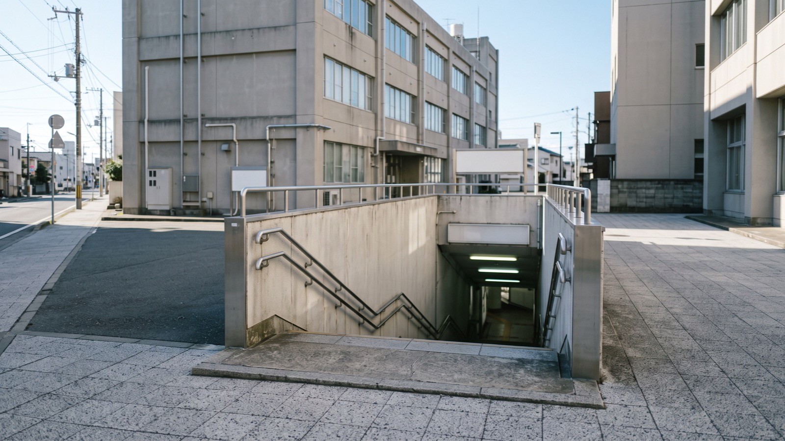 歩道から地下へ降りる階段の入口。指定の数は目標を達成した一方で、地下施設はまだ全体の一部であることを示す。