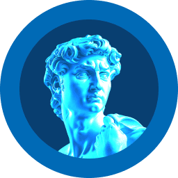 A person with curly hair and glasses smiles at the camera, seated in a cozy workspace with warm lighting.