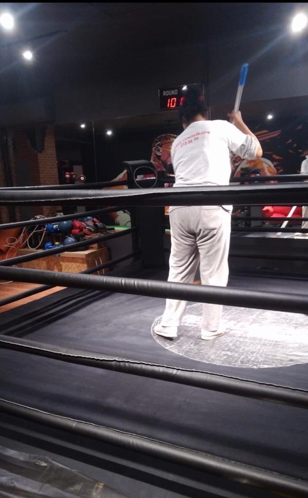man in gray hoodie and blue denim jeans standing on brown wooden parquet flooring