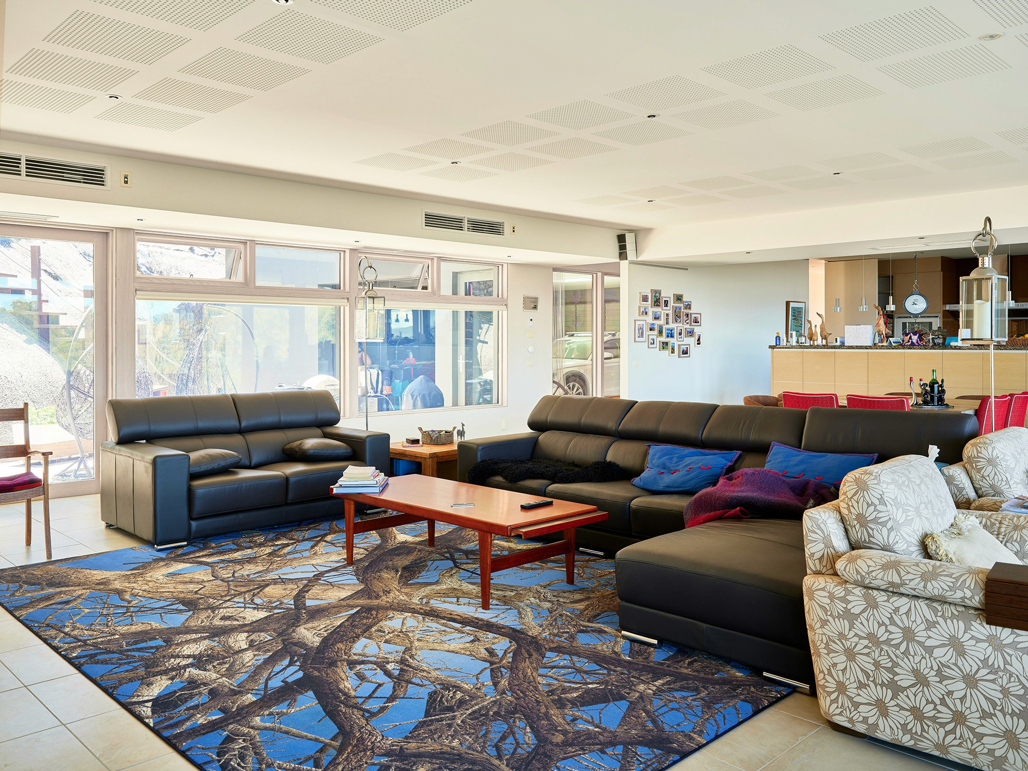 Modern living room with black leather sofas and tree-patterned rug