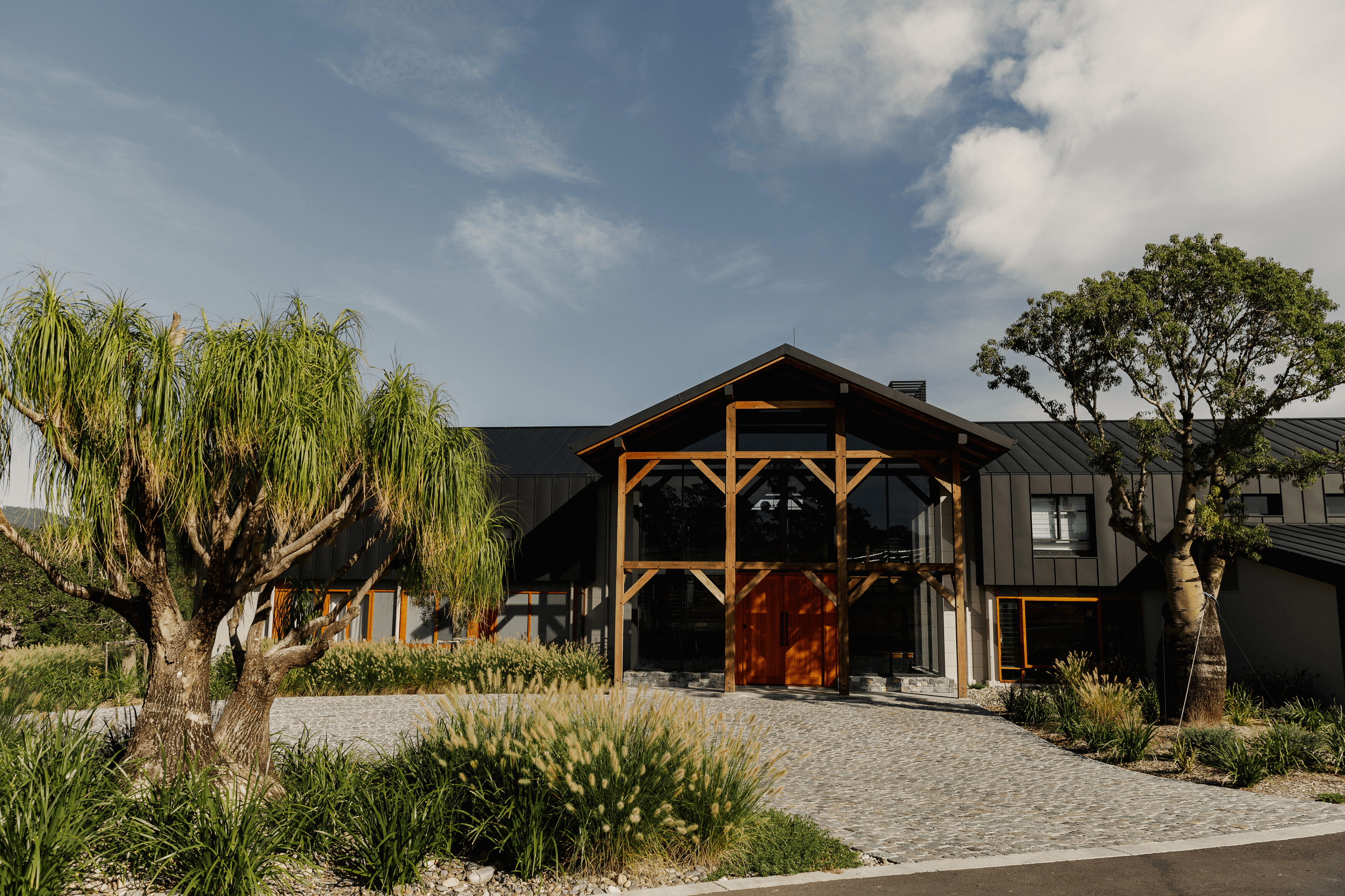 View of the French countryside through a stone villa’s open living room, with sofas and trees framing the scene