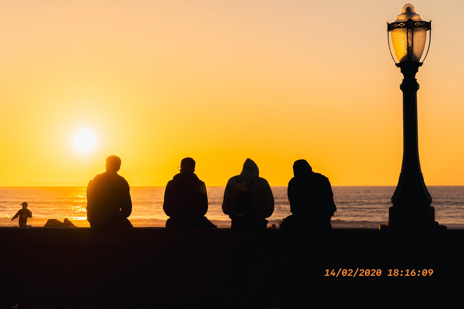 Scène côtière au coucher du soleil, silhouettes et ciel orange