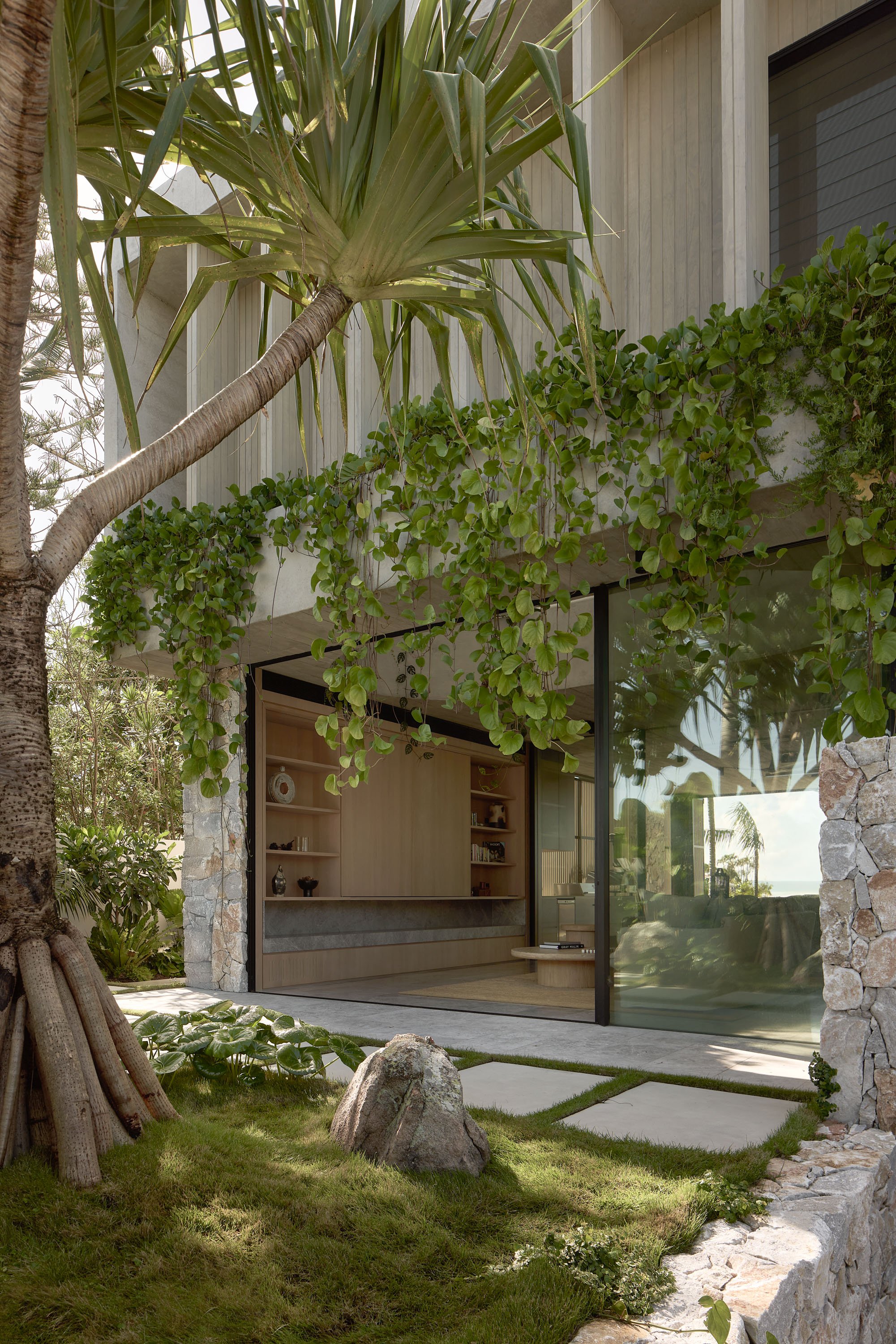 Modern apartment building with a green metal roof, large windows, and glass balconies. The structure features clean lines, wood accents, and a serene ambiance.
