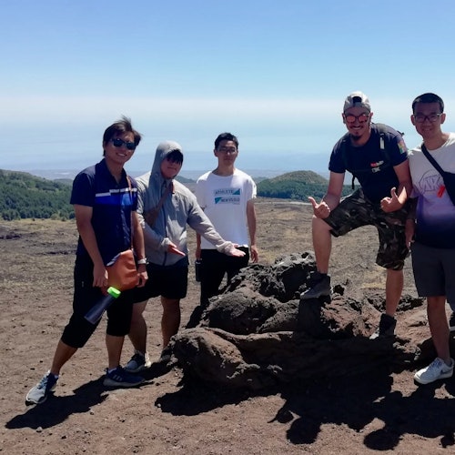 Cinco pessoas posando em uma paisagem rochosa e árida sob um céu limpo. Algumas seguram ou usam equipamento de caminhadas.