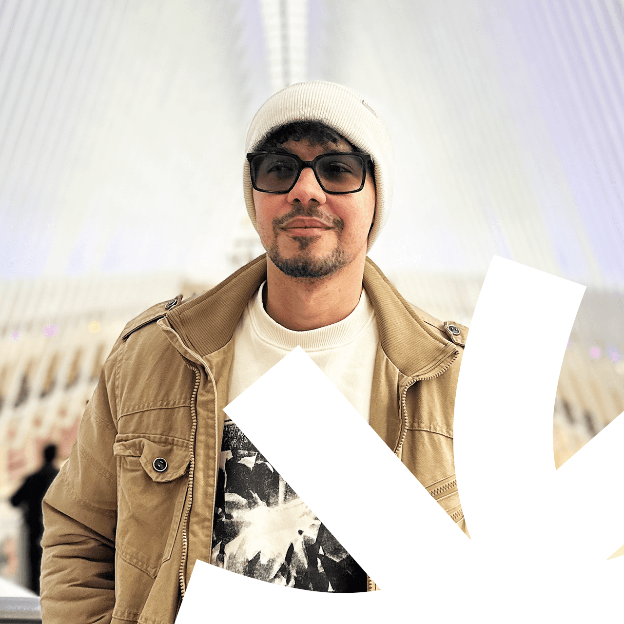 Confident man with short brown hair and beard, wearing a navy zip-up in natural light