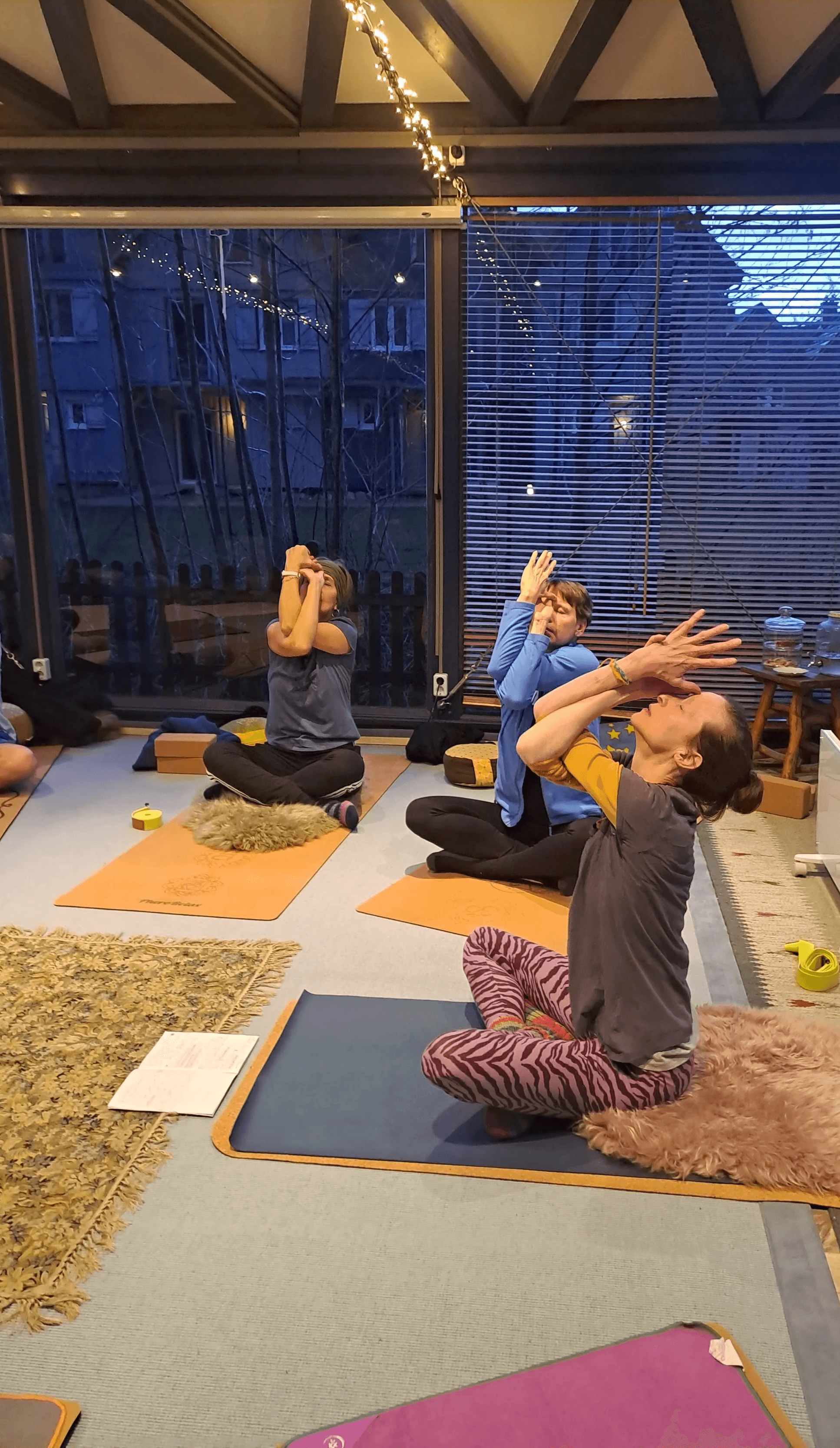 kleine Gruppe auf Yogamatten in Rückbeuge im gekreuzten Sitz mit Adlerarmen (Aufwärmung)