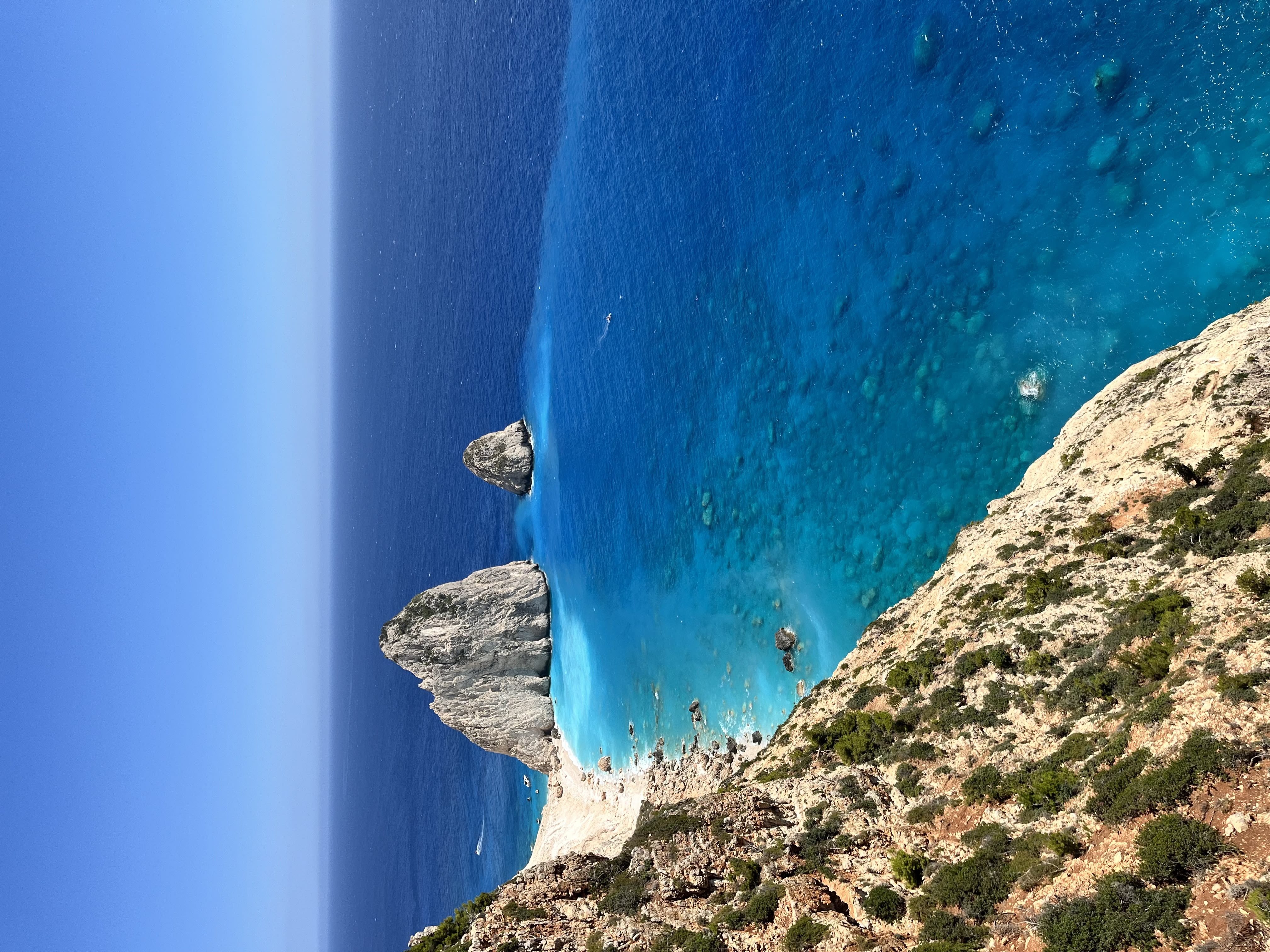 Smiling young man with short hair poses against a dark background, wearing a green button-up shirt.