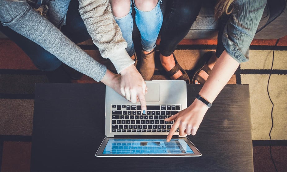 Multiple people pointing their fingers at a laptop screen