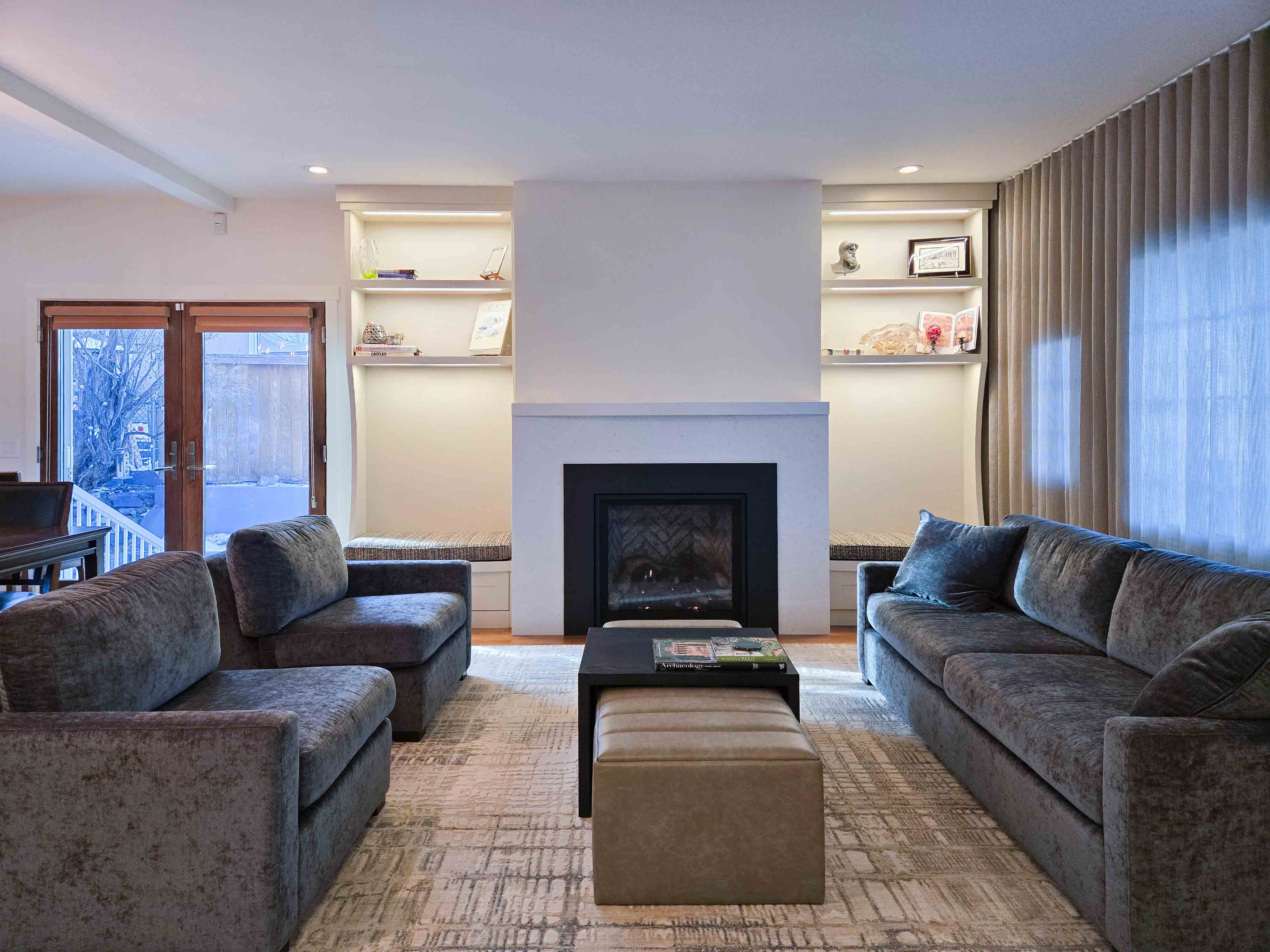 Gas fireplace with illuminated custom, cream millwork flanking it.