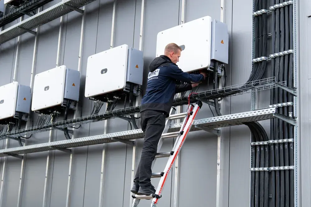 Mann auf Leiter installiert Wechselrichter für Solaranlage