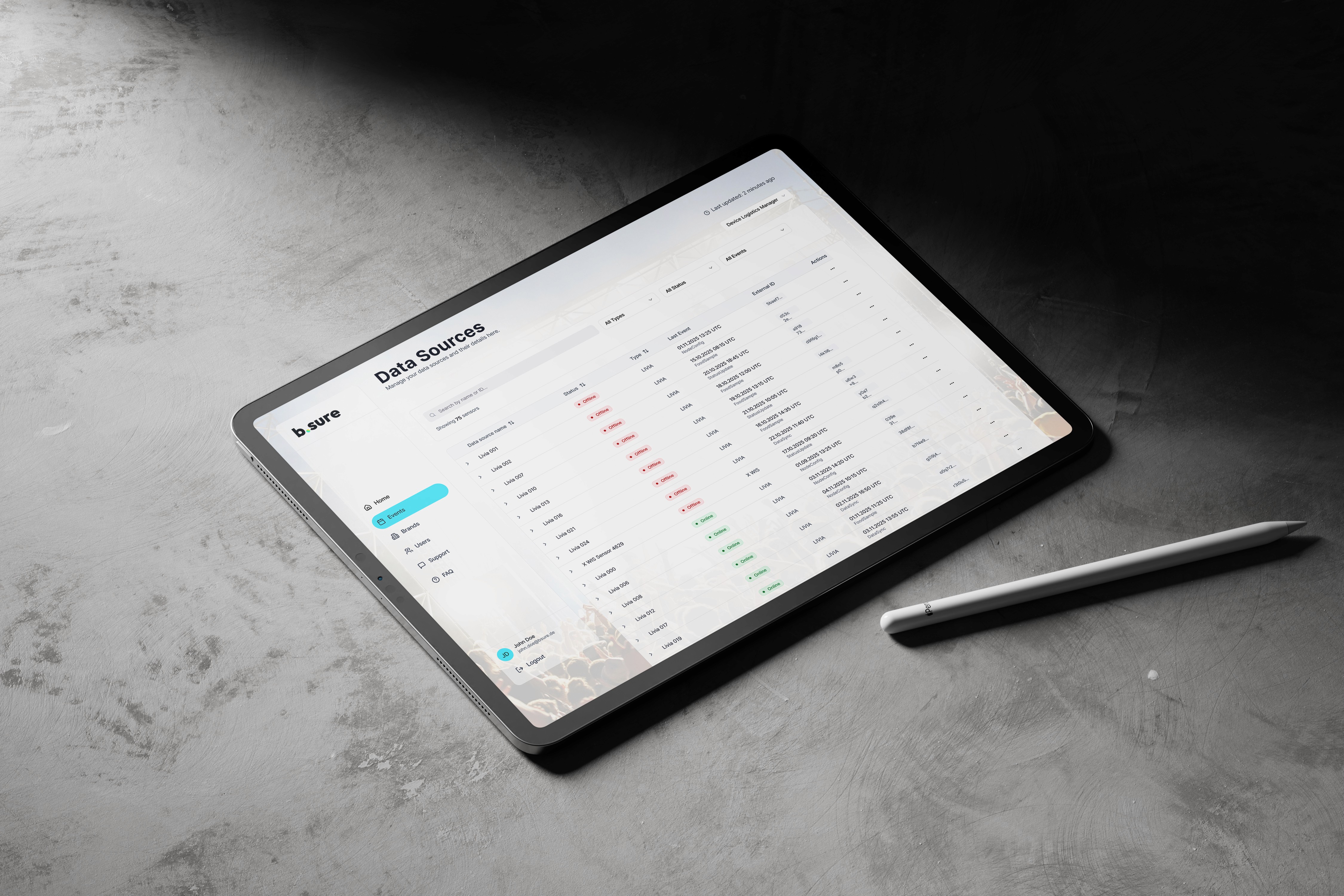 Tablet displaying a b.sure data table interface with a stylus resting beside it on a textured stone surface.