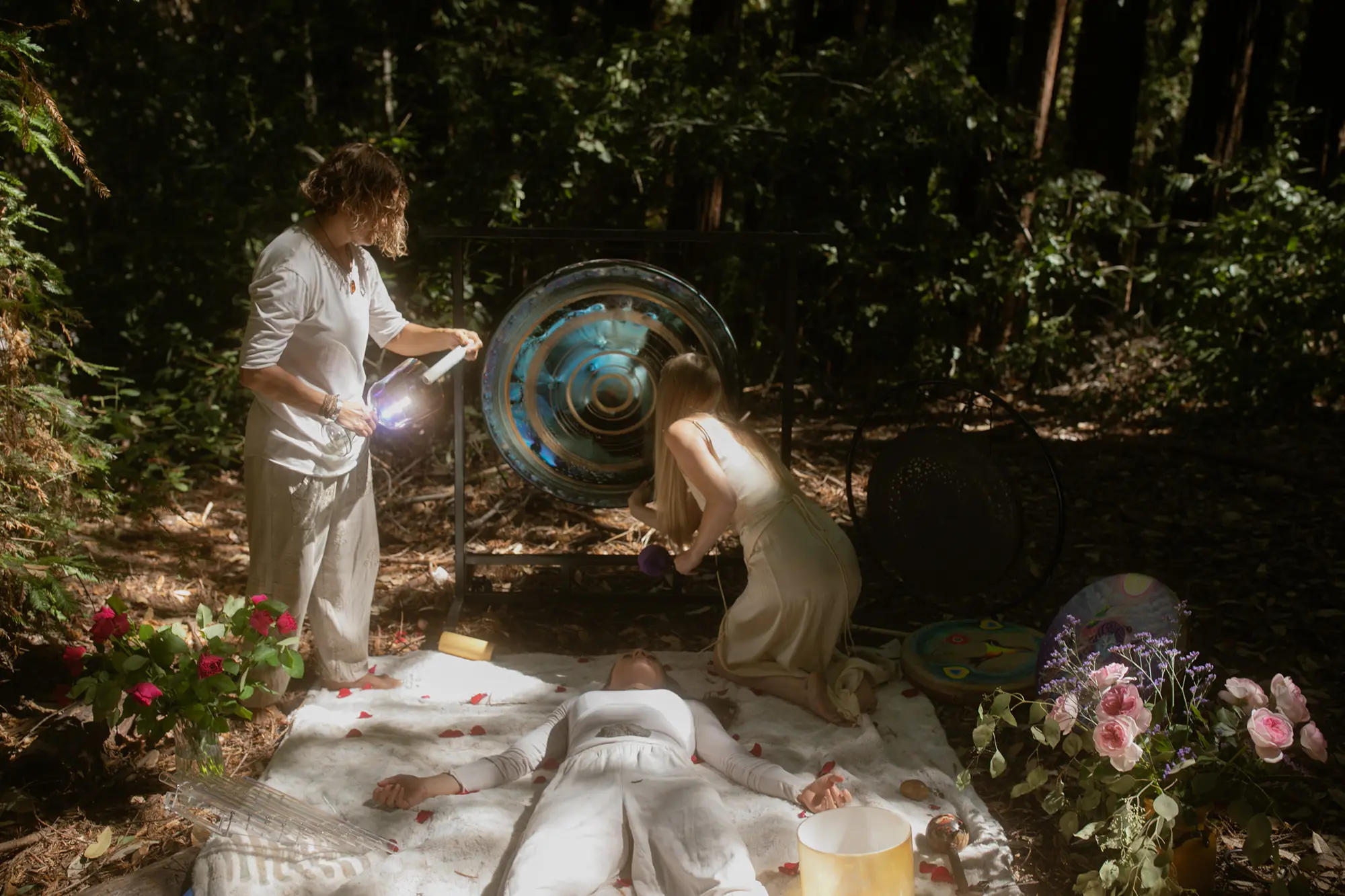 Guide performing sound healing with a gong during an intimate outdoor ceremony