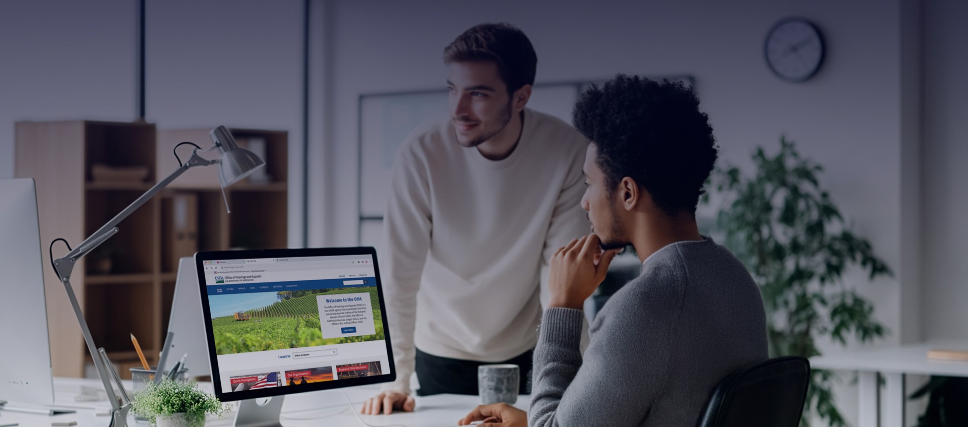 Two designers collaborating on a web interface in a bright, open office.