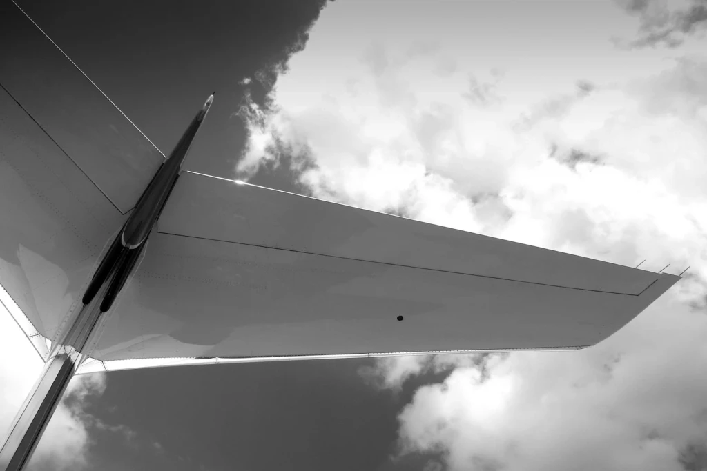 Close-up of a private jet wing against a cloudy sky