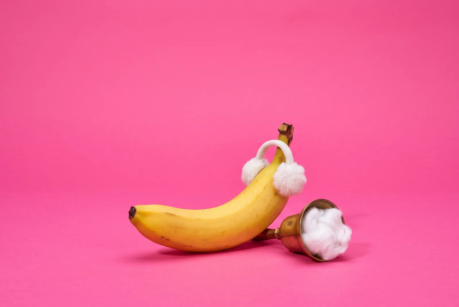 A banana in tiny earmuffs beside a muffled brass bell, muting words to turn off sensitive content on X