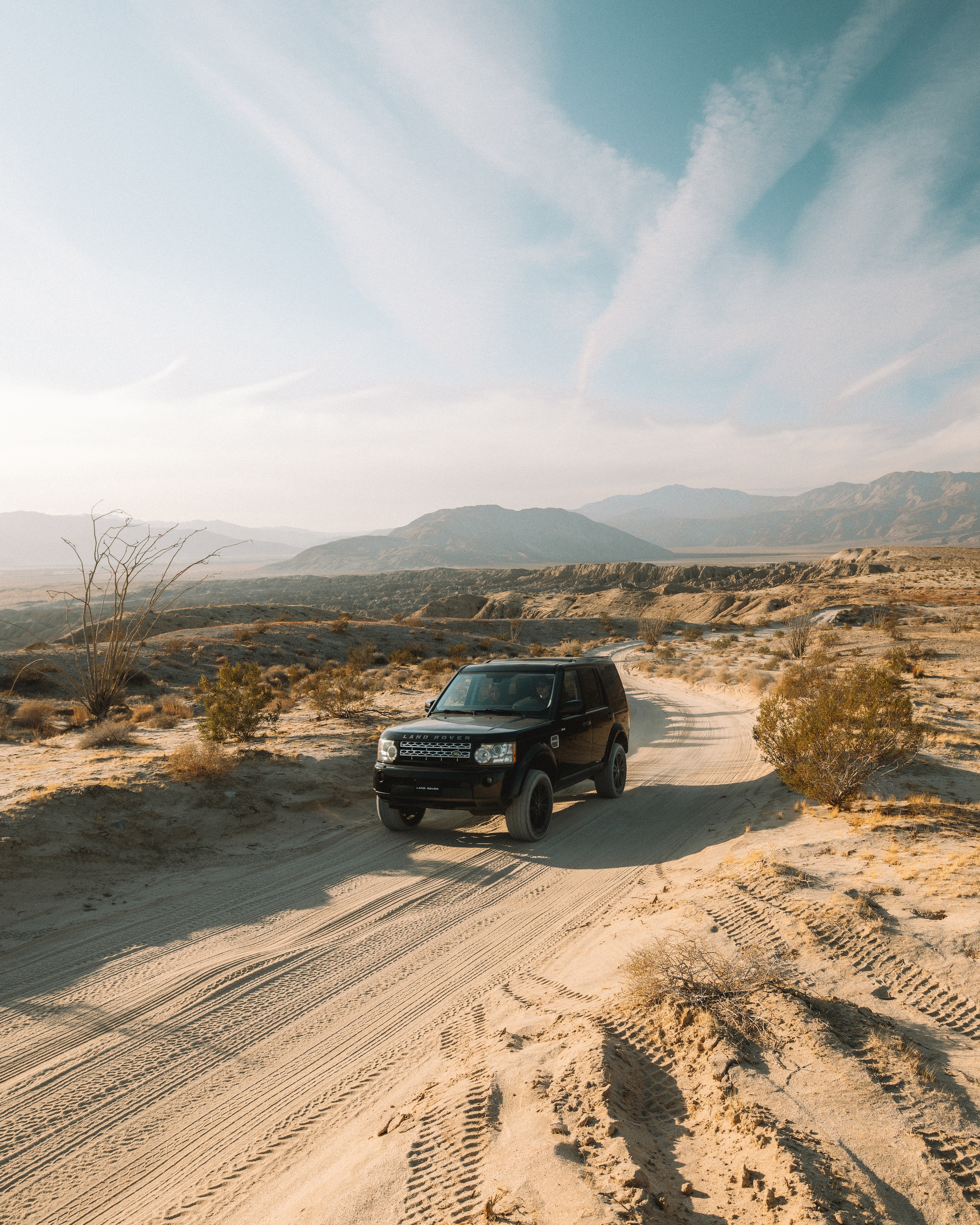 A SUV driving on a sandy road