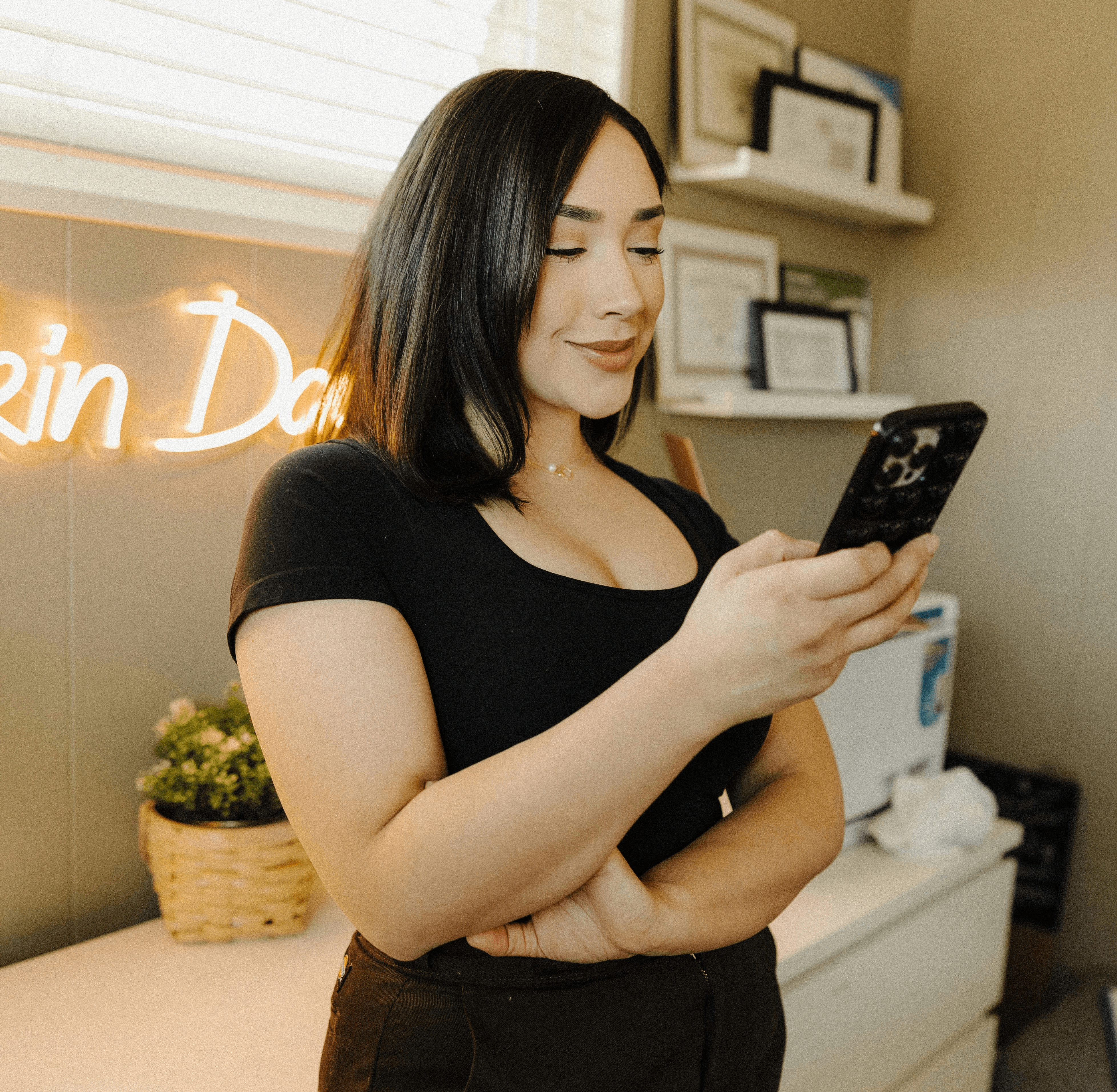 a woman standing in front of a counter holding a cell phone