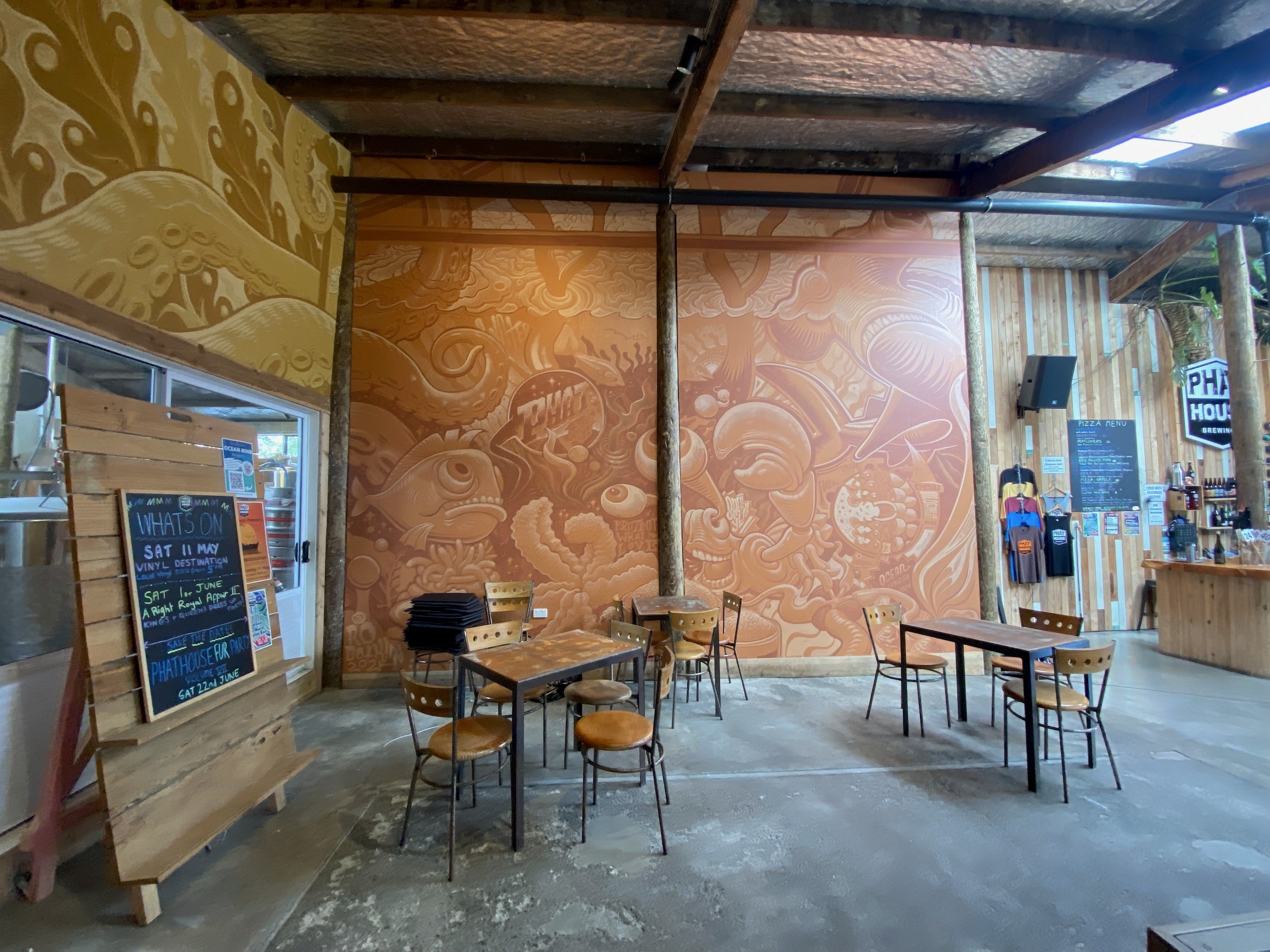 The brewery hall's ochre and gold walls rise above tables, chairs and a chalkboard.