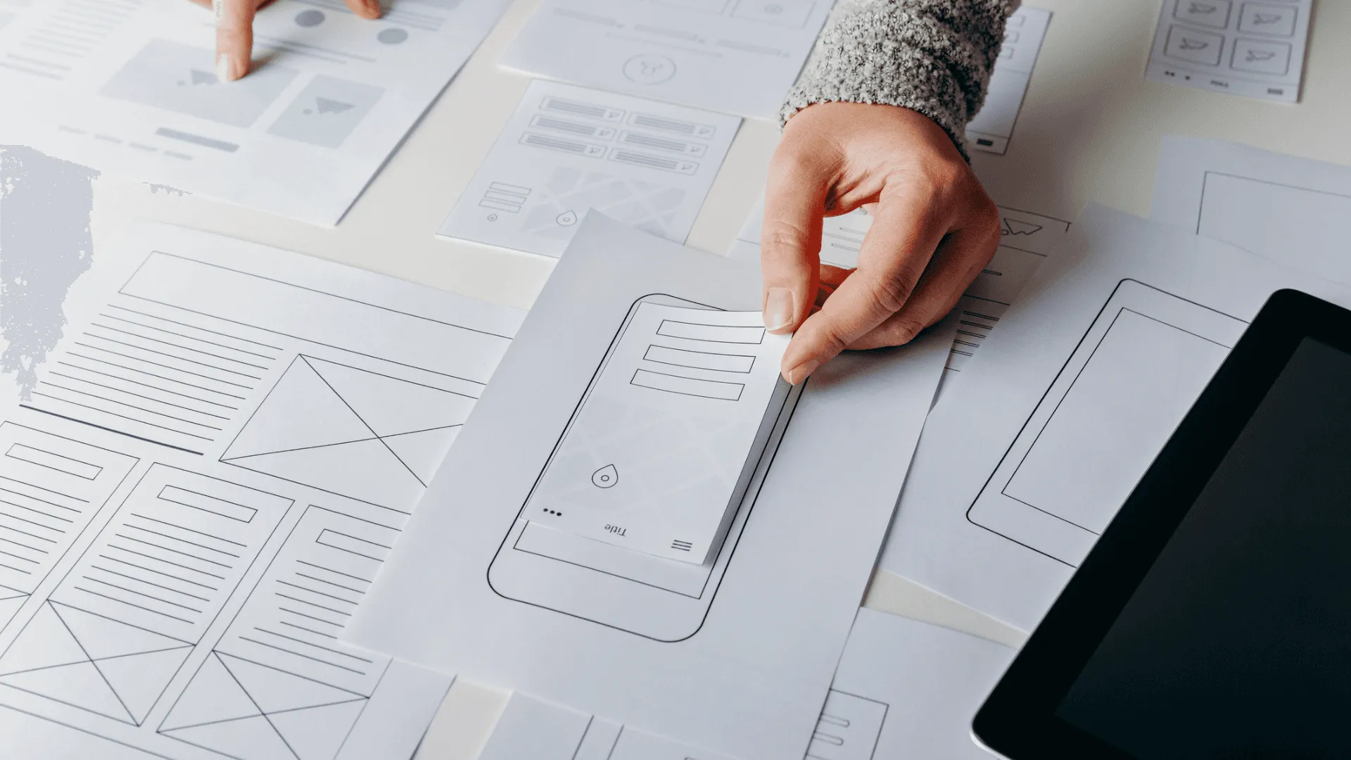 A person laying out wireframe options within paper templates