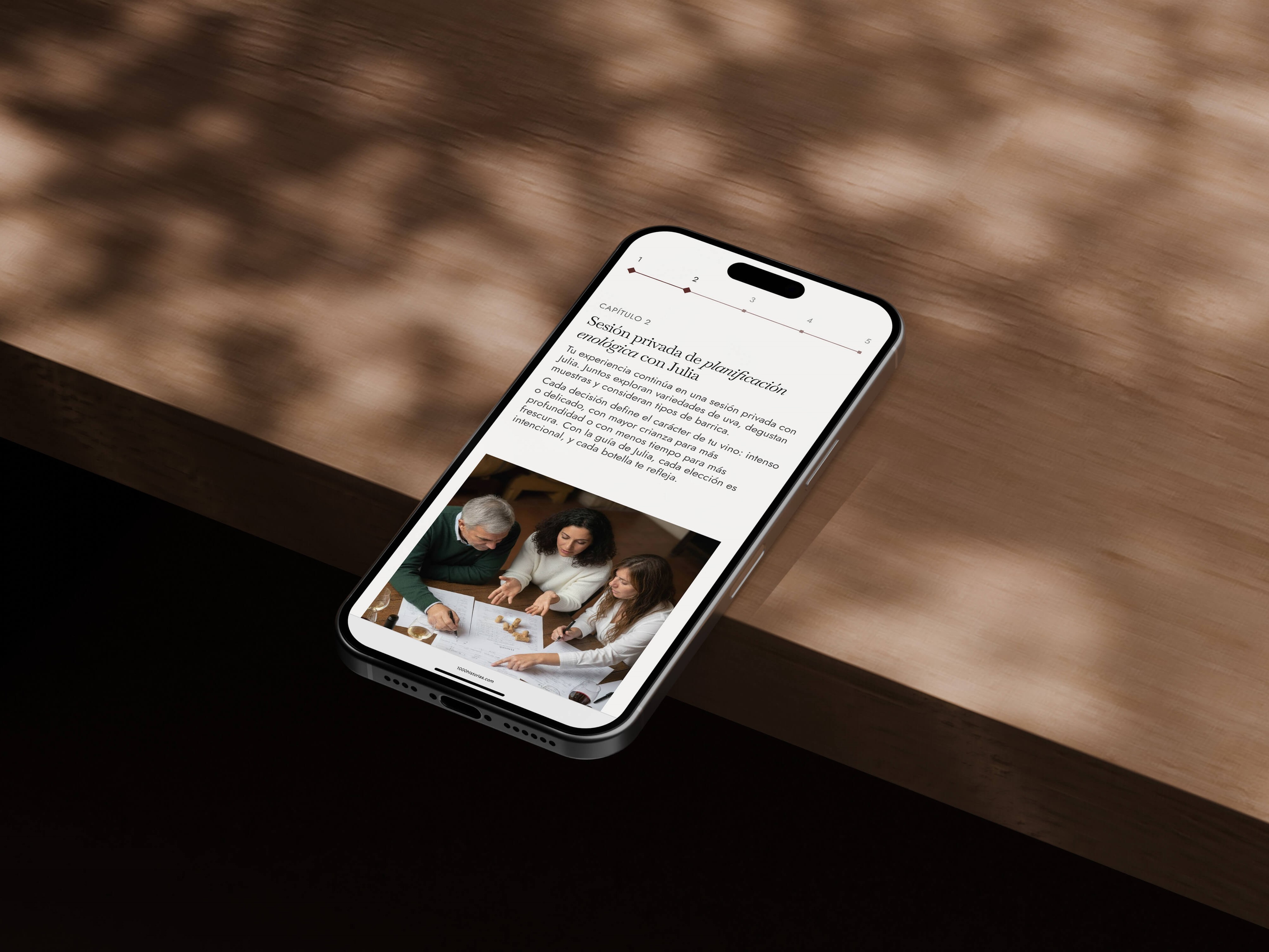 1000 Historias website displayed on an Iphone laying on a wood table