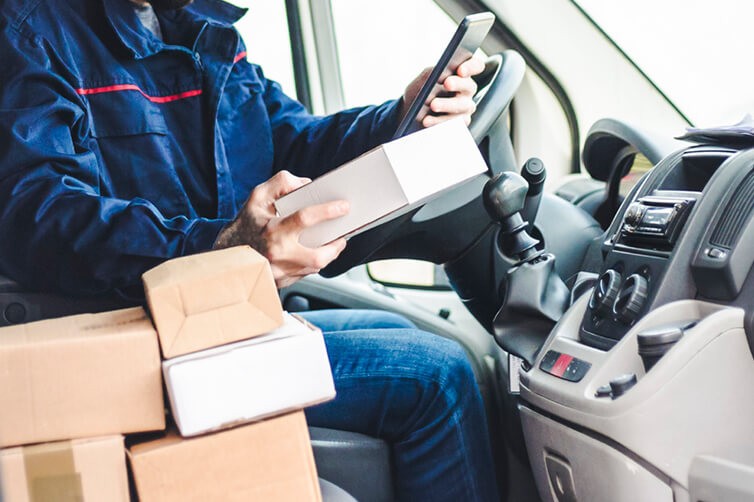 Courier in van handling parcels with tablet