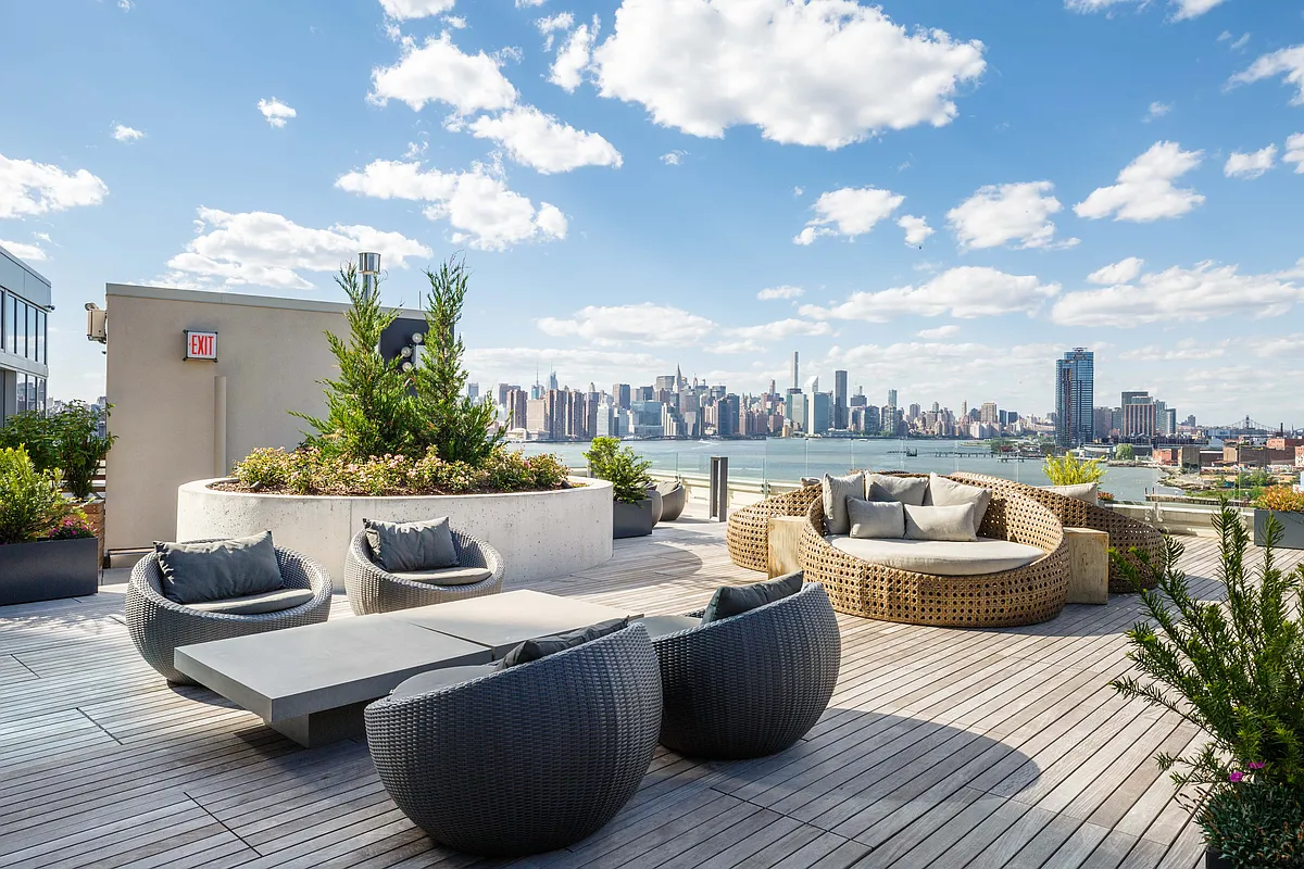 A rooftop patio featuring stylish furniture and a panoramic view of the city skyline.