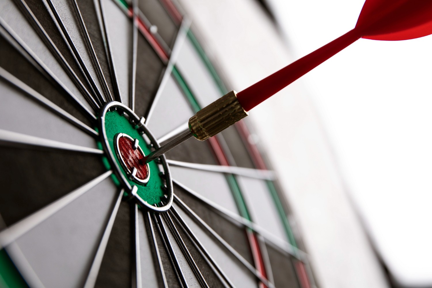 Red dart hitting a dartboard bullseye.