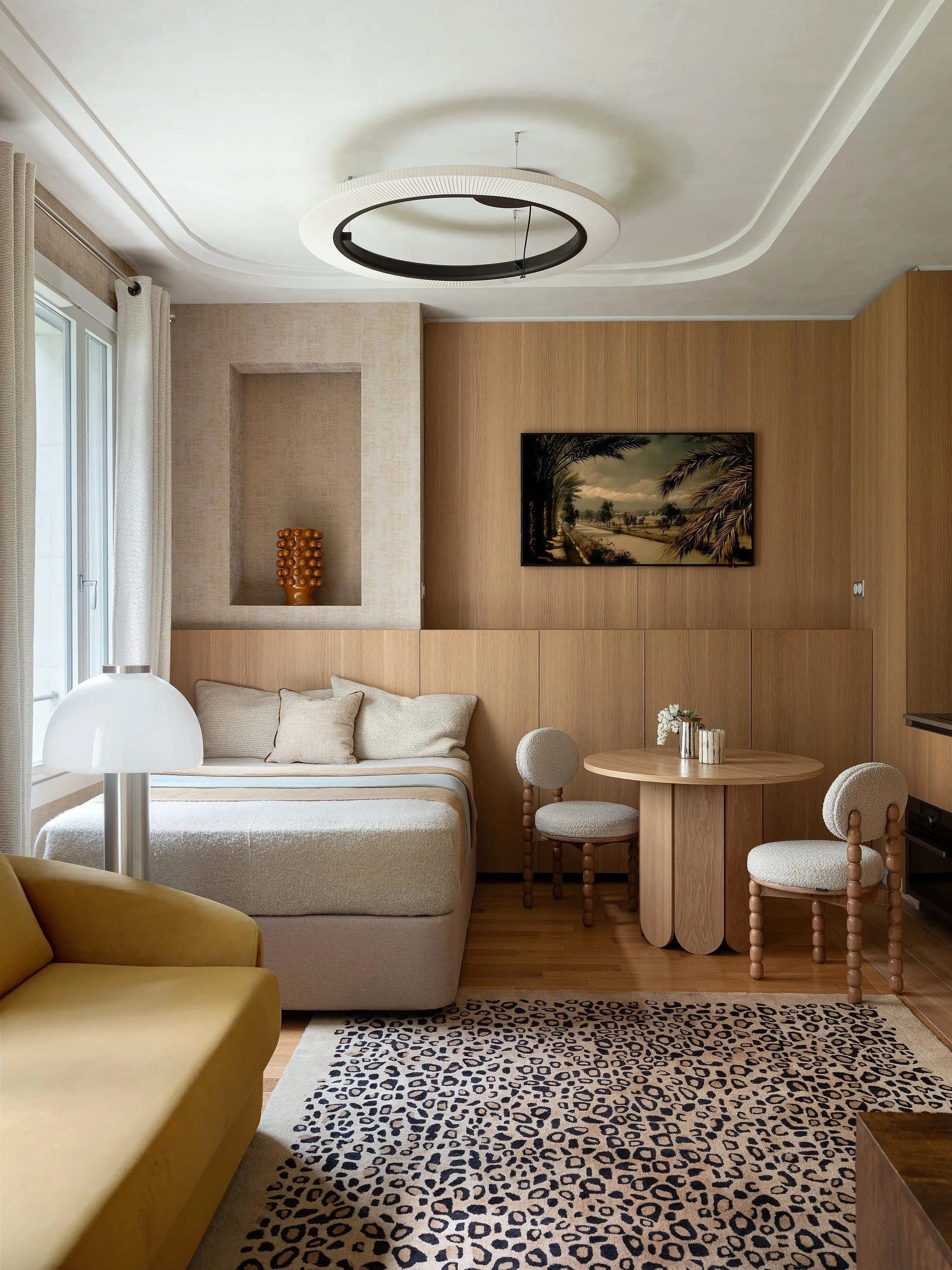 Optimisation d'un studio de 29 m² à Paris 7 avec menuiserie sur-mesure en chêne clair intégrant cuisine, coin repas et chambre.