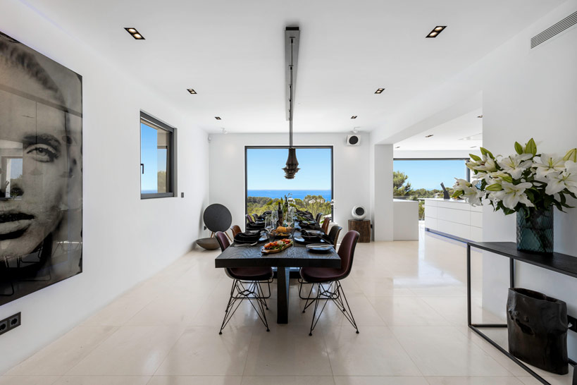 Indoor breakfast dining area with sea view, modern art and open-plan kitchen setting.