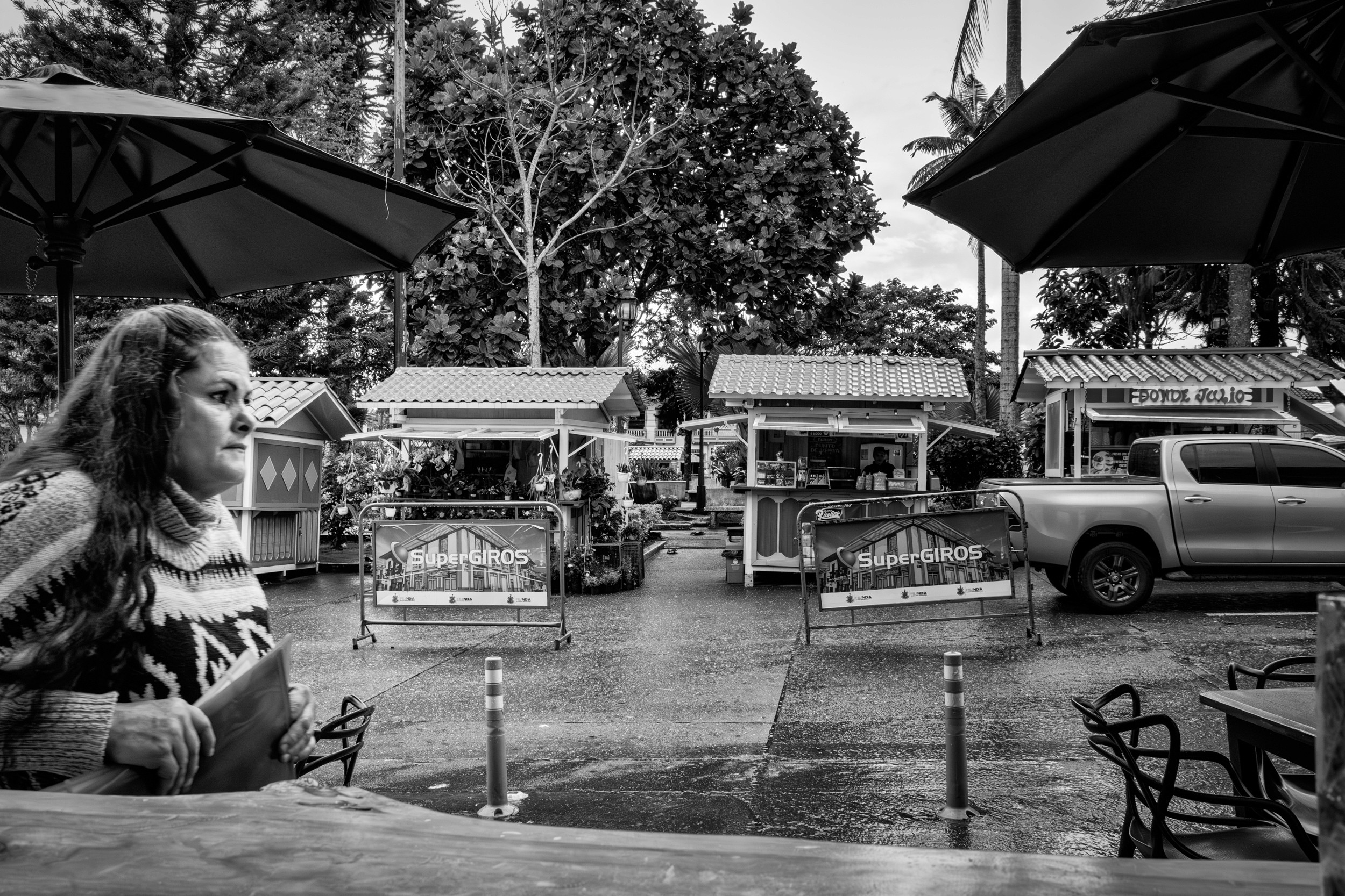 Rainy street scene with people passing by a bar window.
